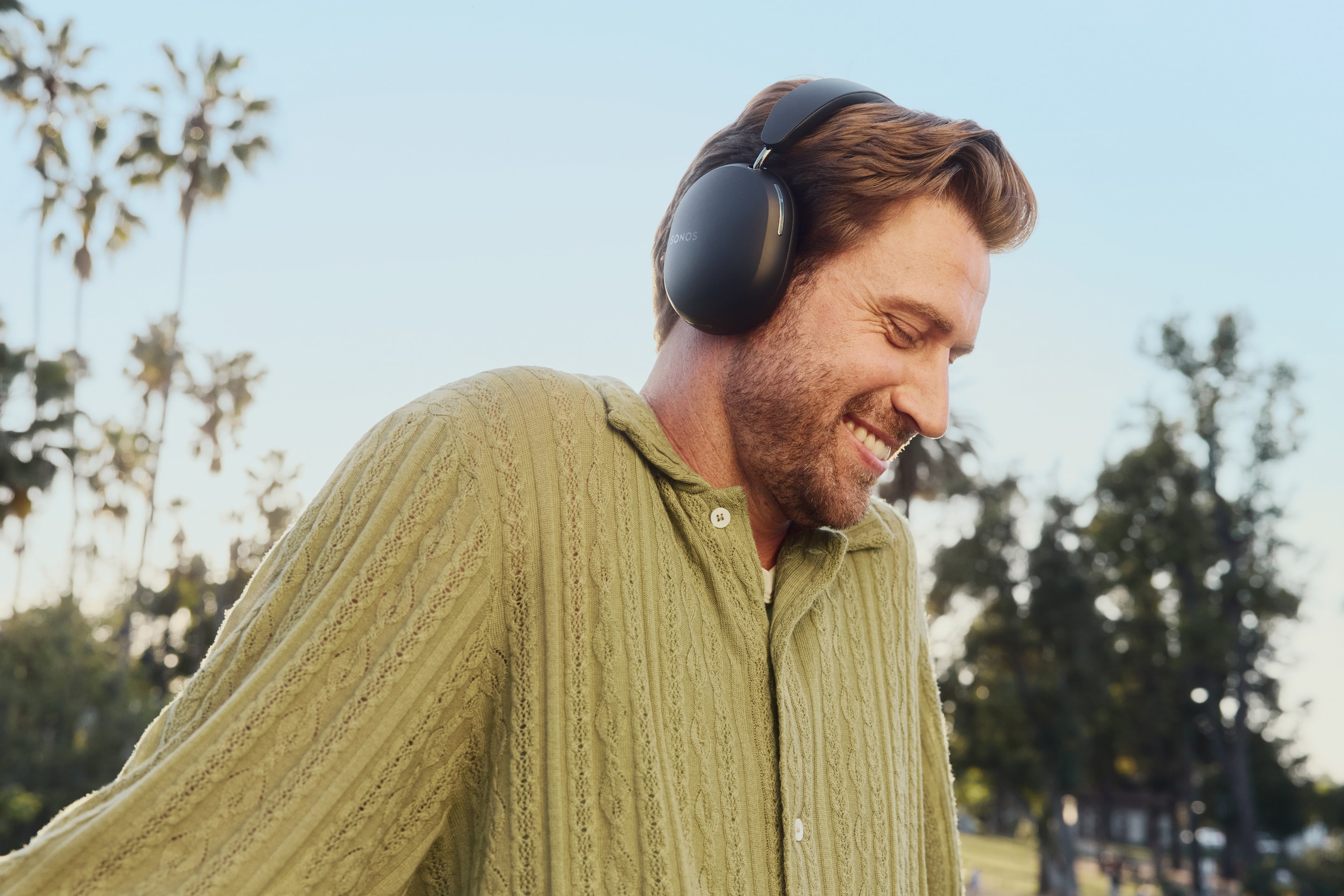 User wearing black Sonos Ace headphones in the park