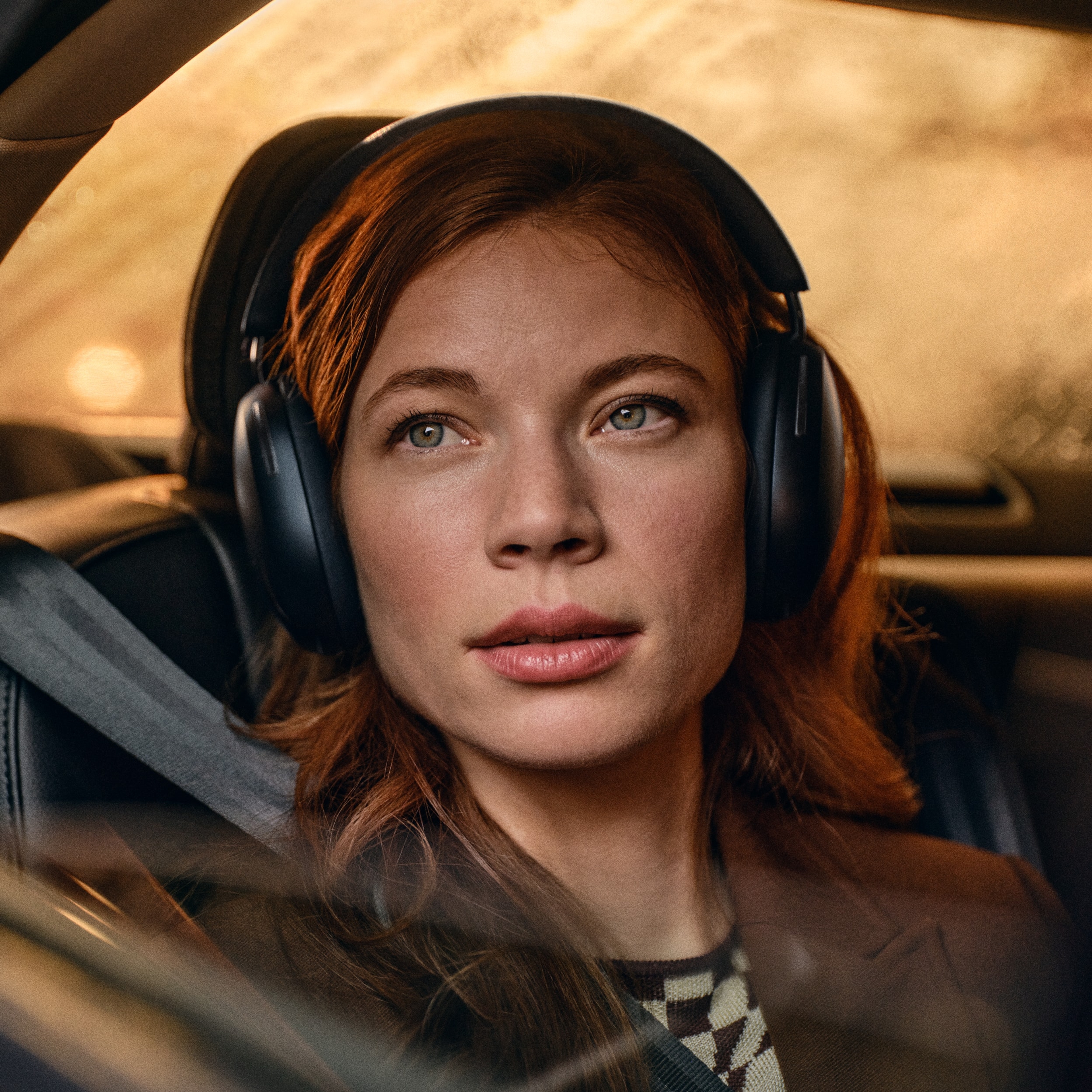 Vrouwelijke gebruiker in een auto met een zwarte Sonos Ace koptelefoon op