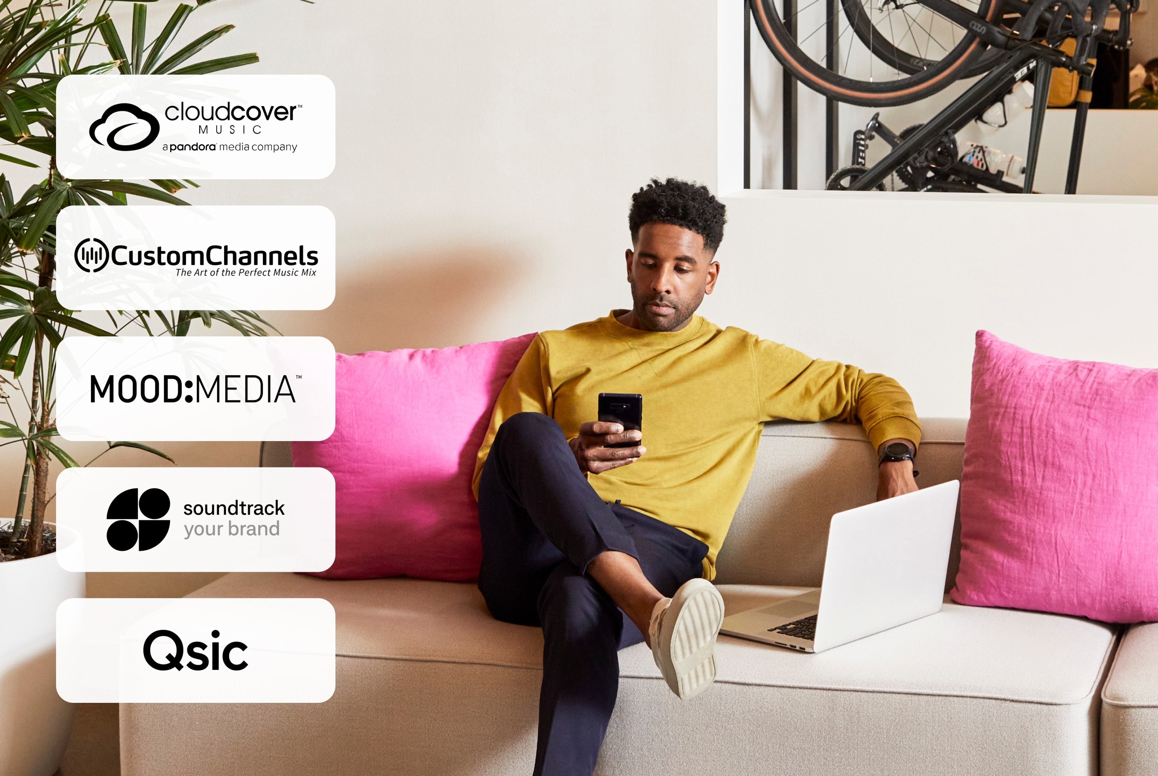 Music logos overlay and person on the couch with phone and laptop