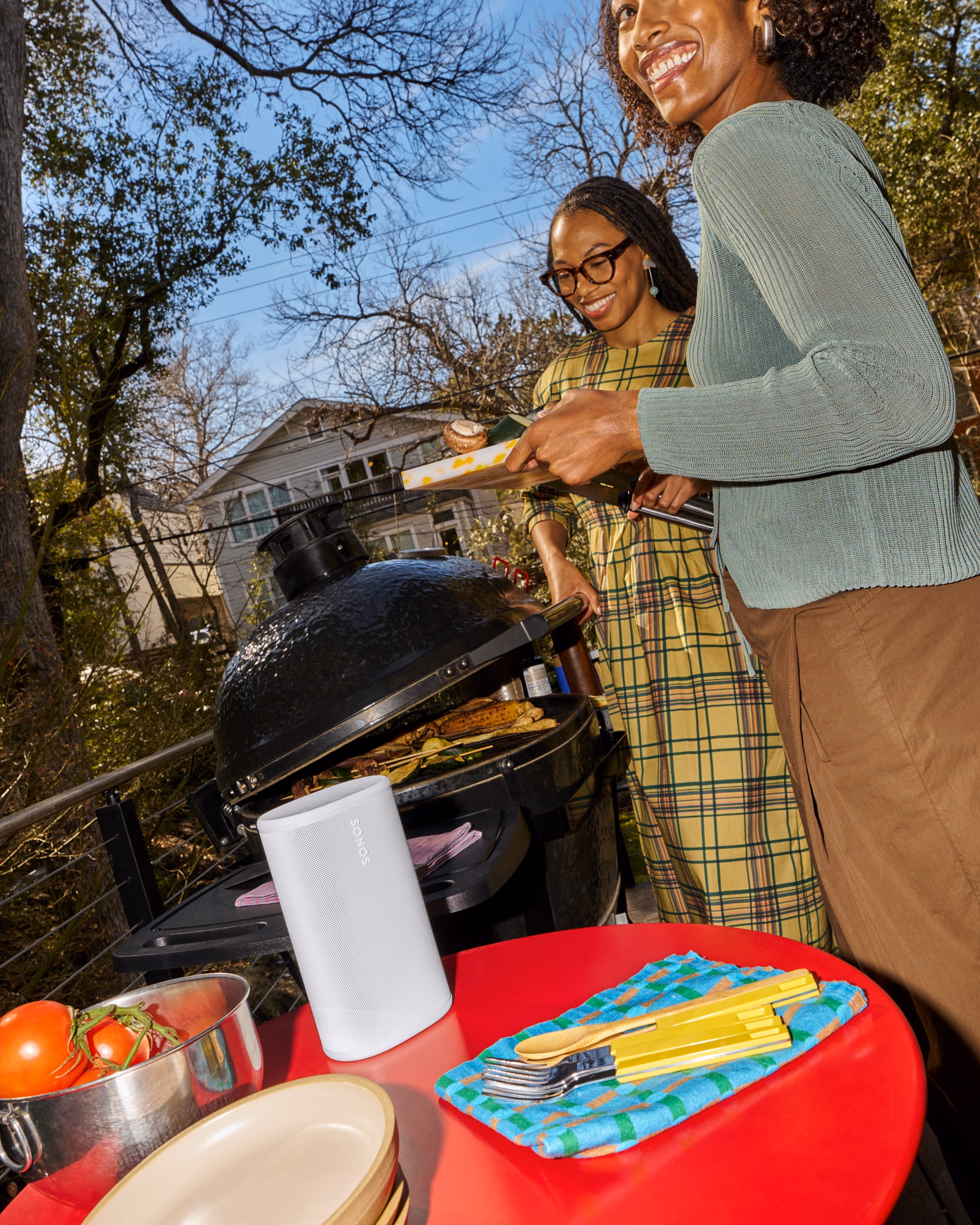 Sonos Playスピーカー(ホワイト)で音楽を聴きながら、庭でバーベキューをしている二人の友人