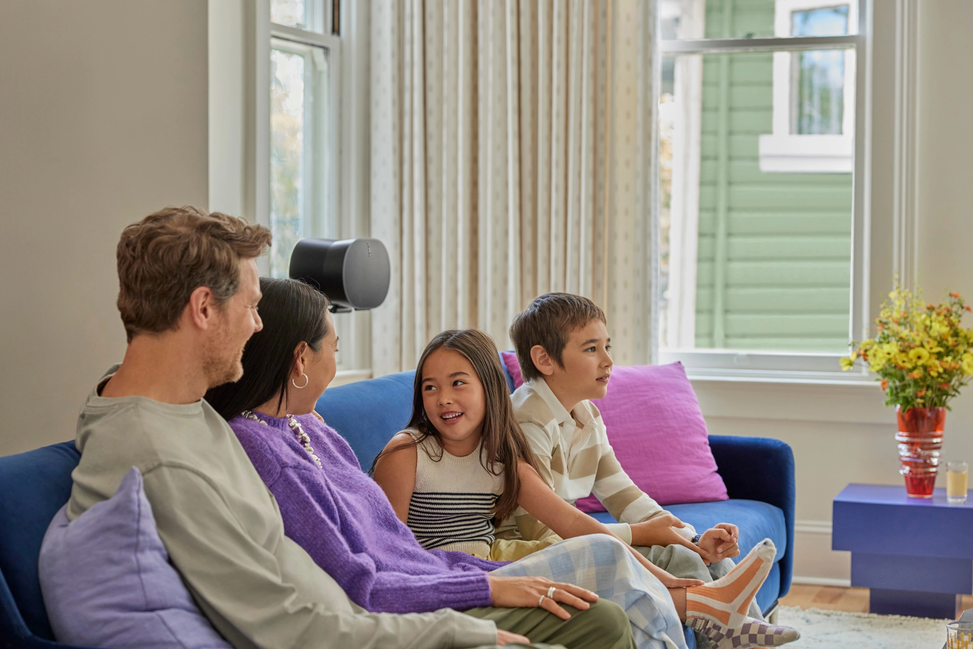 Family conversing on a couch in front of a black Era 300 on a stand