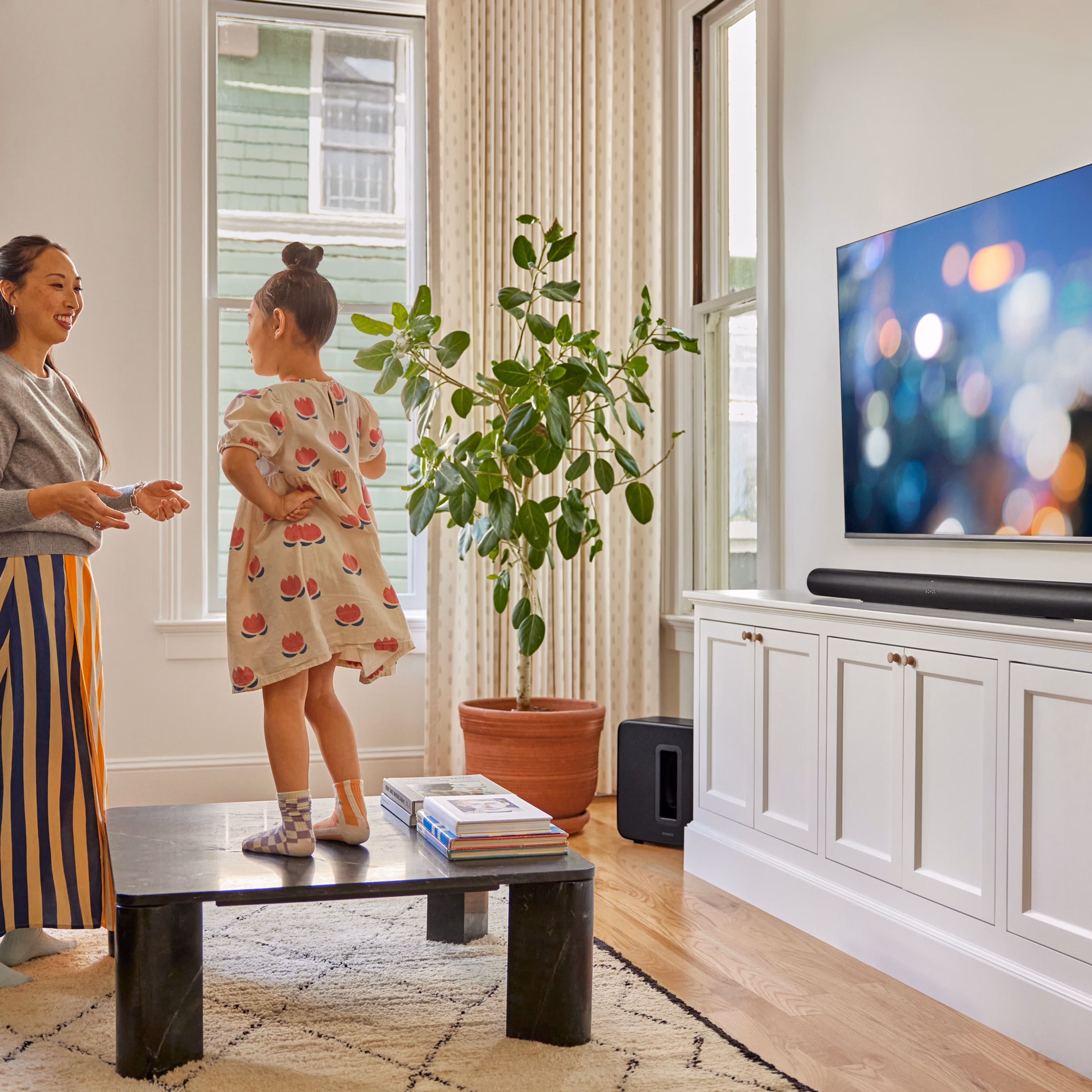 A mother and daughter playing in front of the TV with a black Arc Ultra
