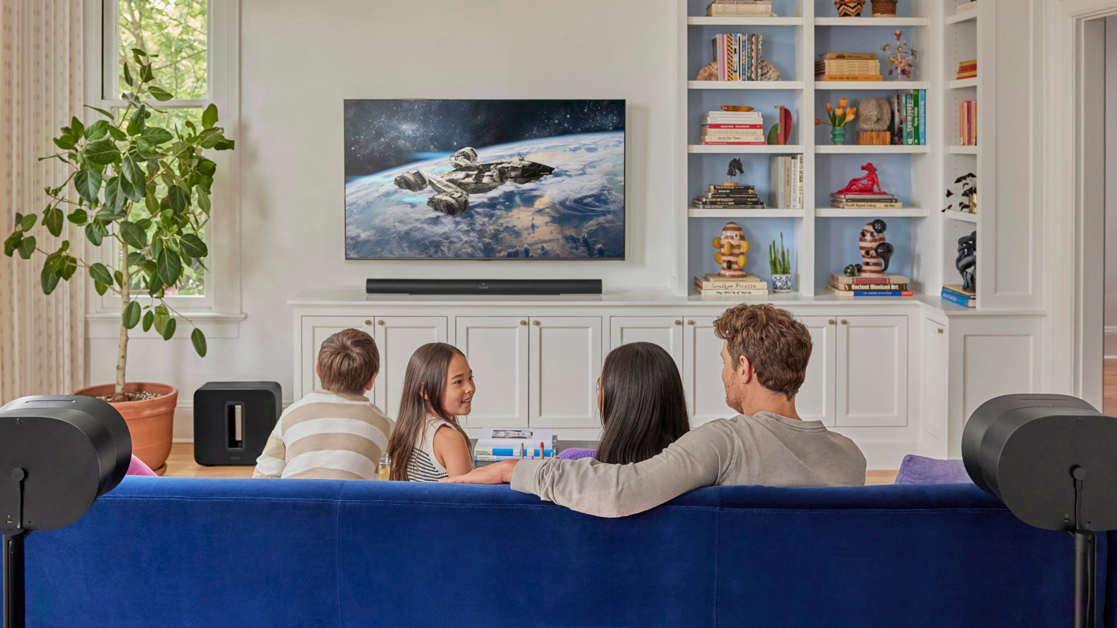 A family on the couch watching a film with a Sonos Arc Ultra, Sub 4, and Era 300 speakers home theatre setup