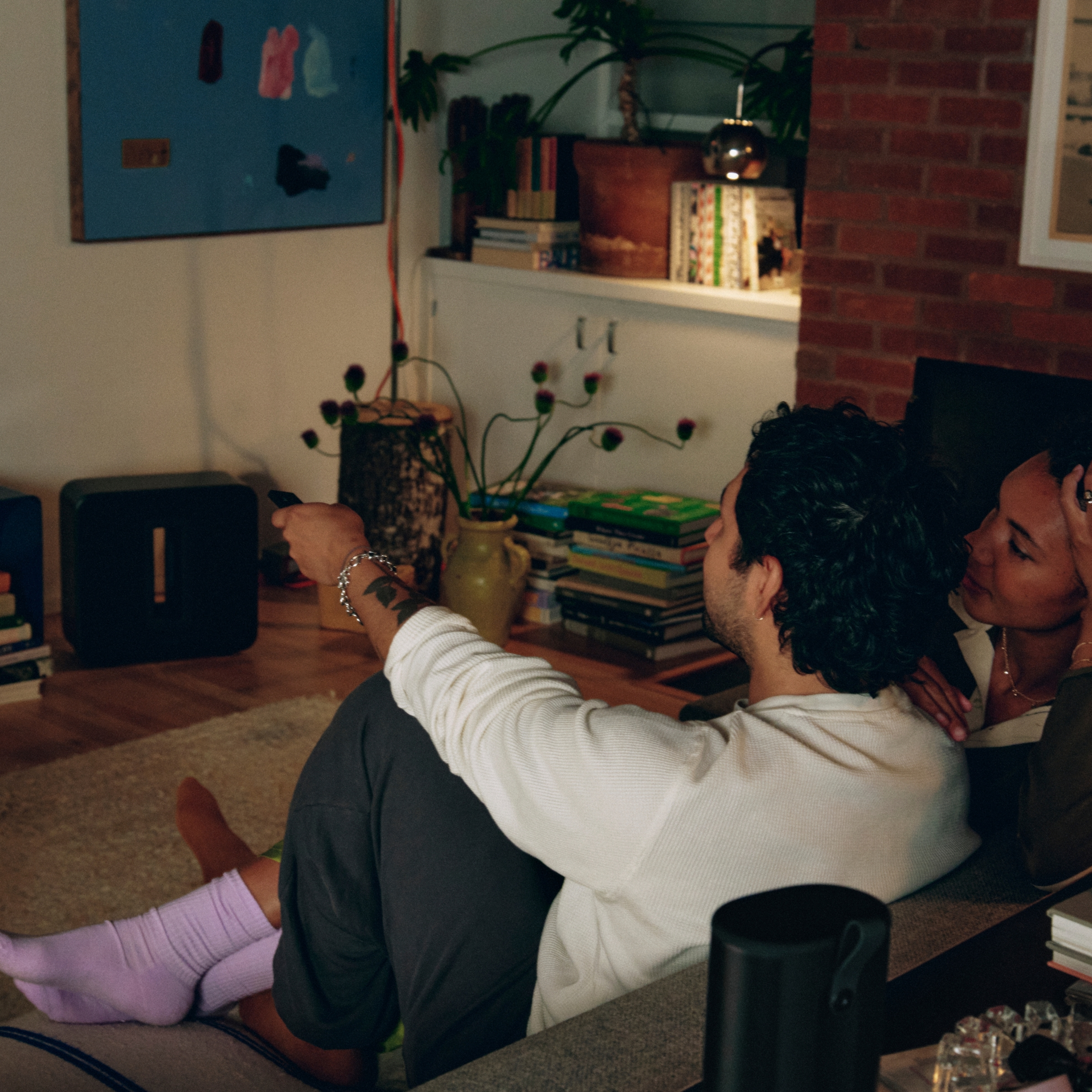 A person using the TV remote sitting on a couch in a living room
