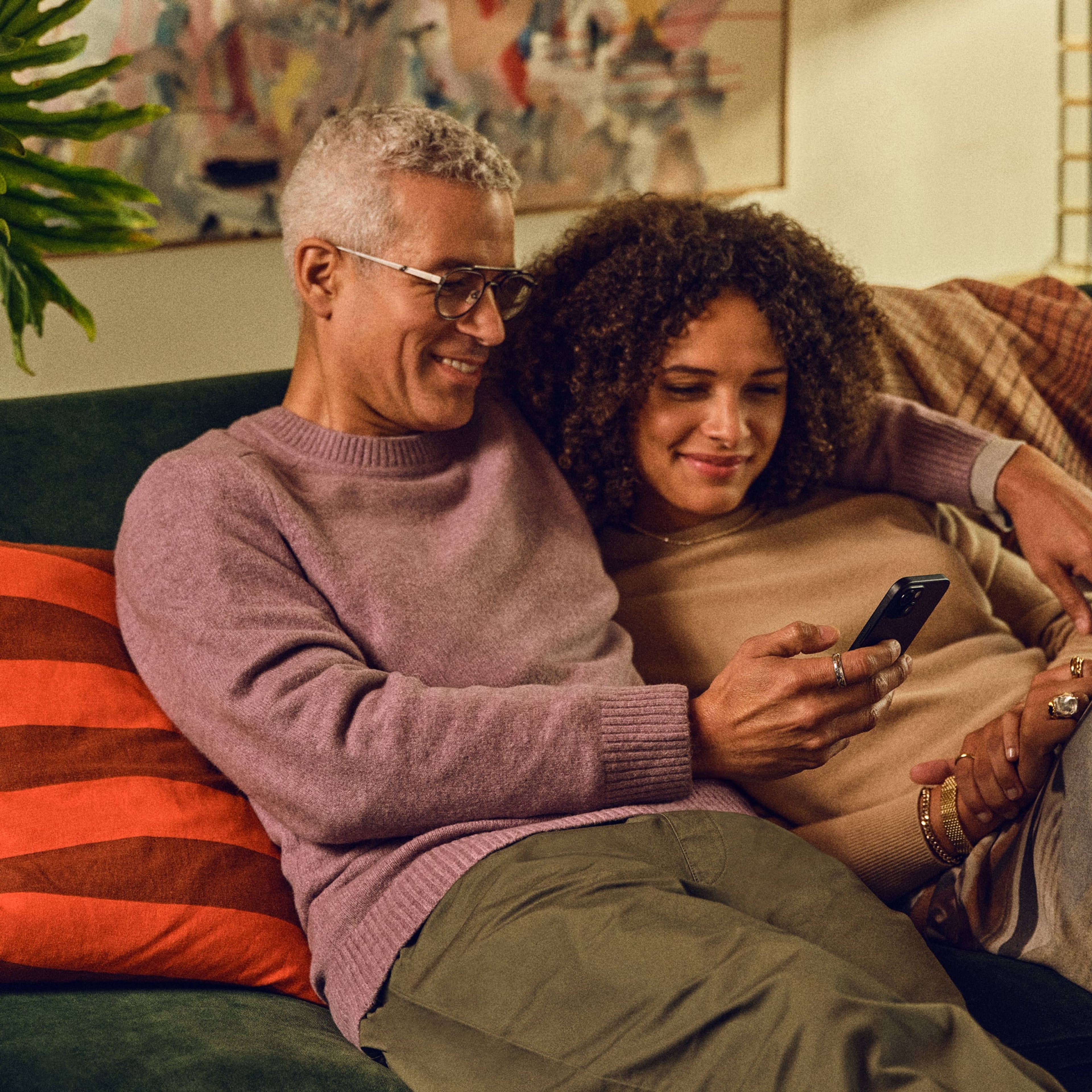 Una pareja sentada en un sillón usando la app Sonos