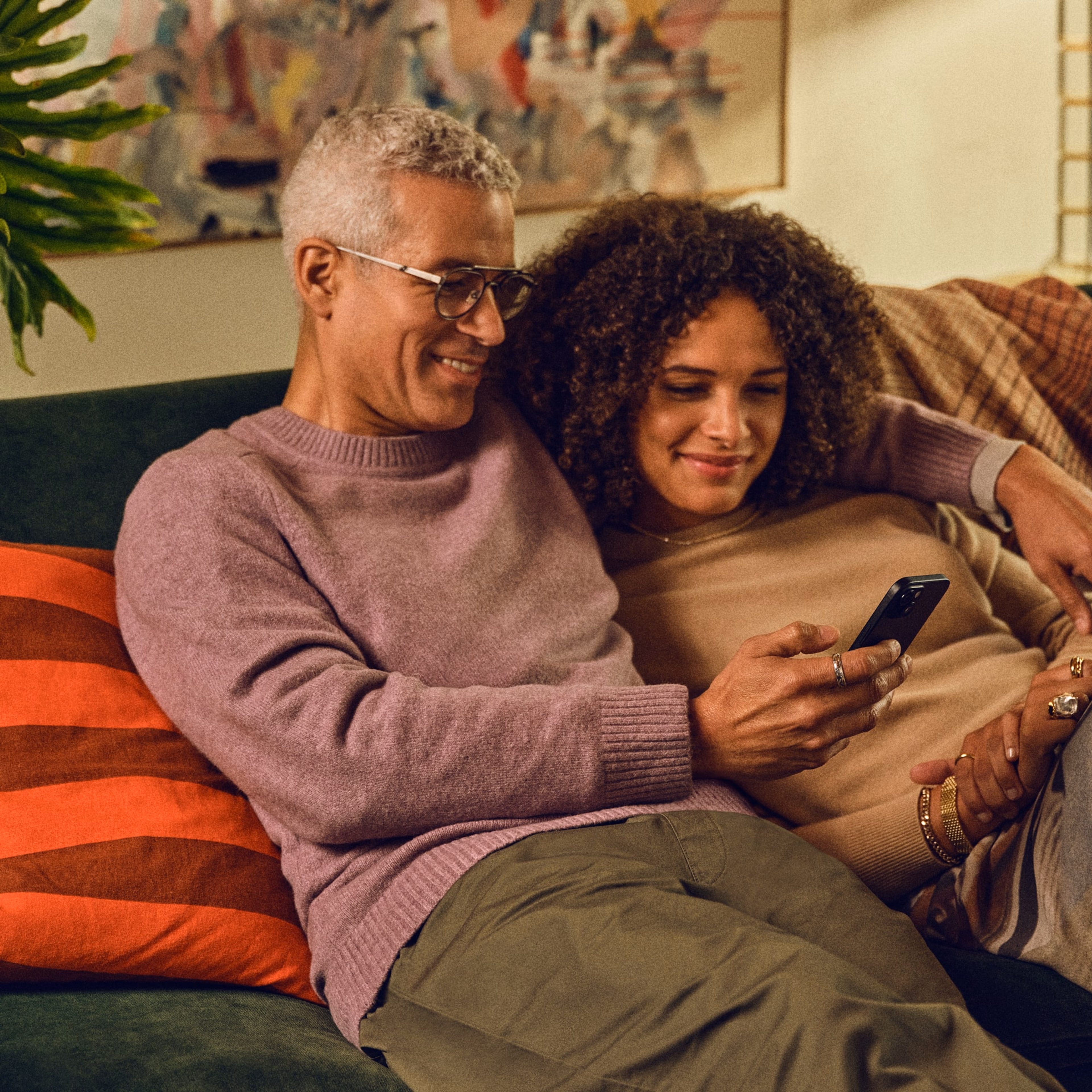 A couple sitting on the couch using the Sonos app