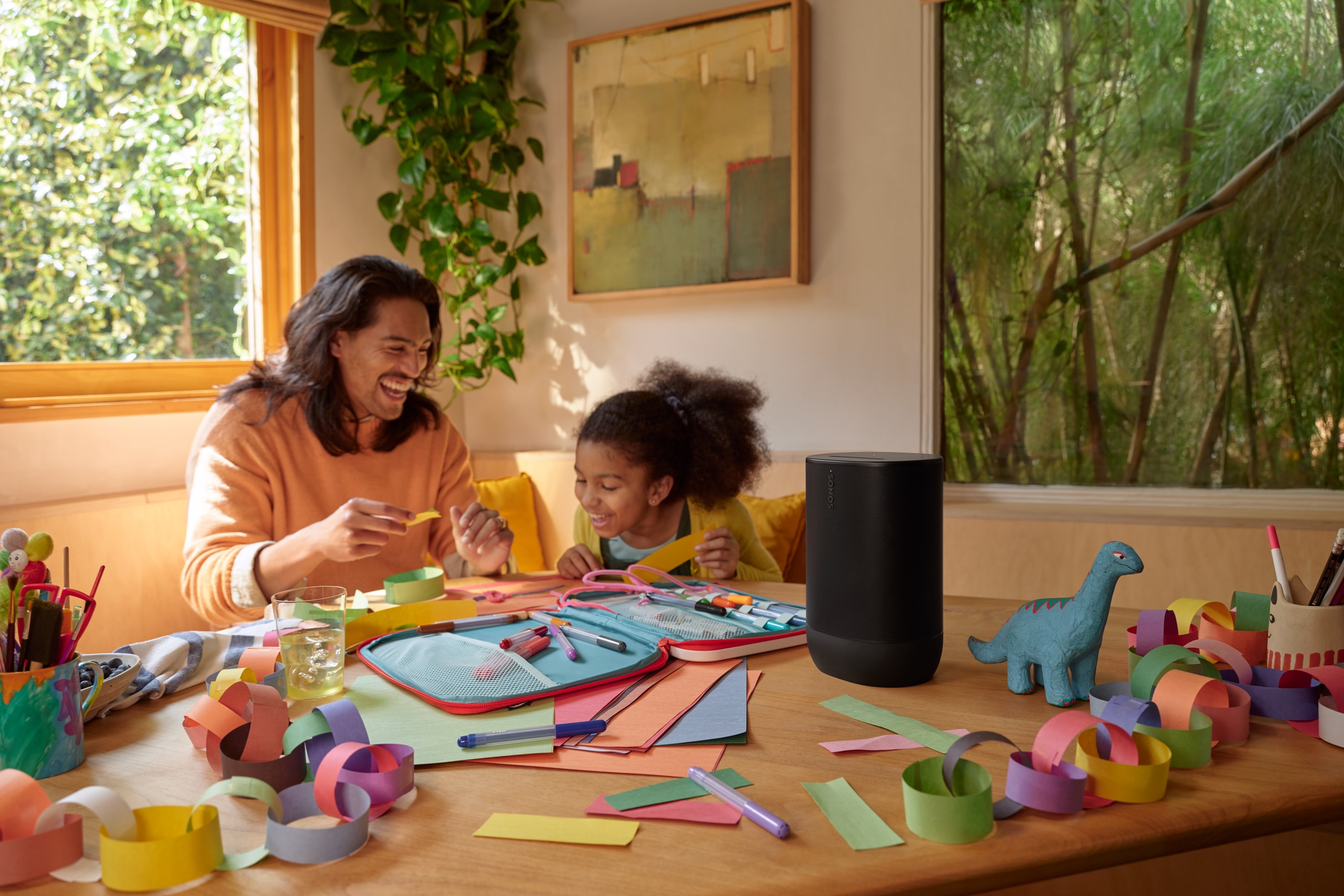 A picture of a father and daughter at the kitchen table doing arts and crafts while listening to a black Sonos Move 2