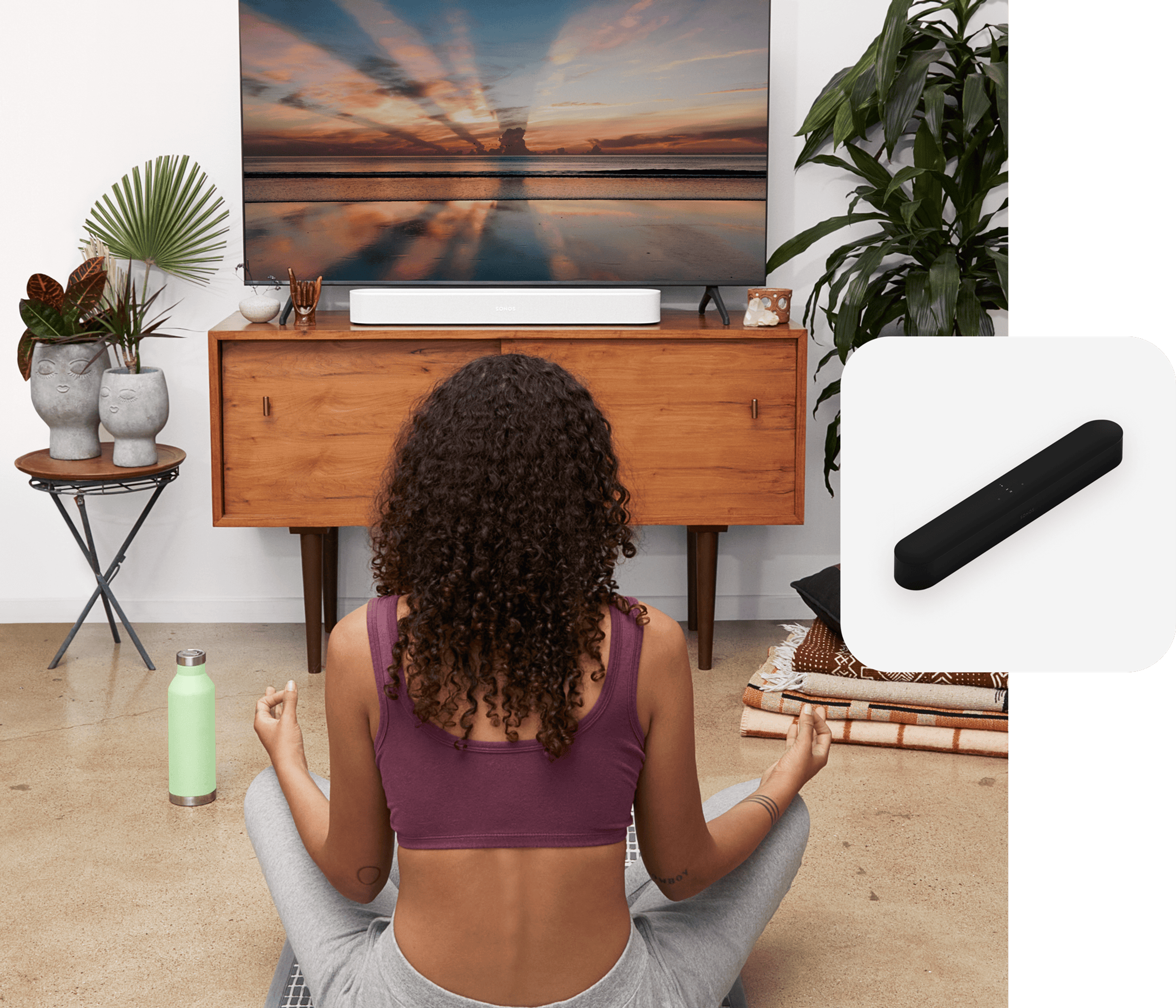 Woman doing yoga in front of TV media console with a white Sonos Beam soundbar