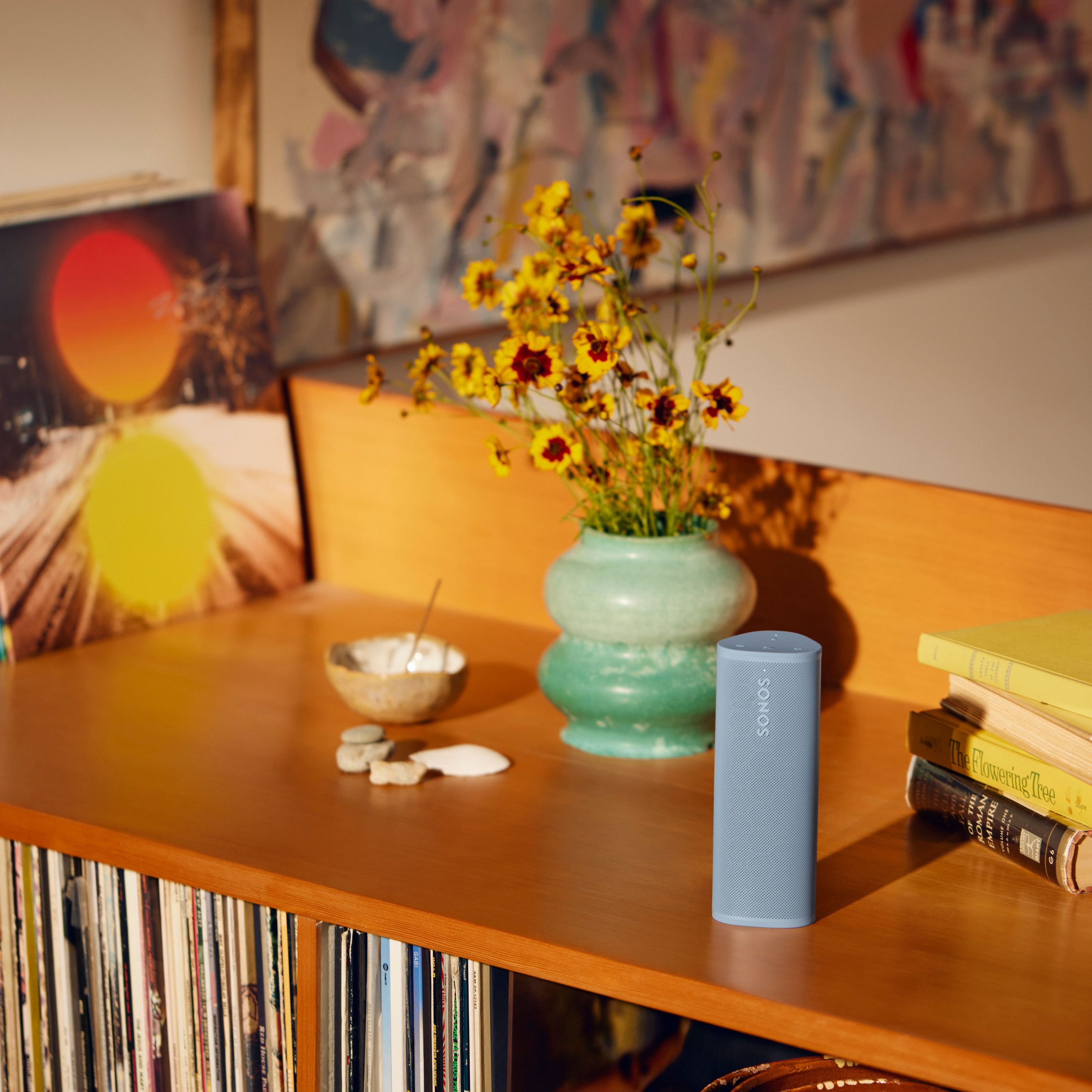 Sonos Roam 2 couleur Wave posé sur une étagère à côté de fleurs dans un vase