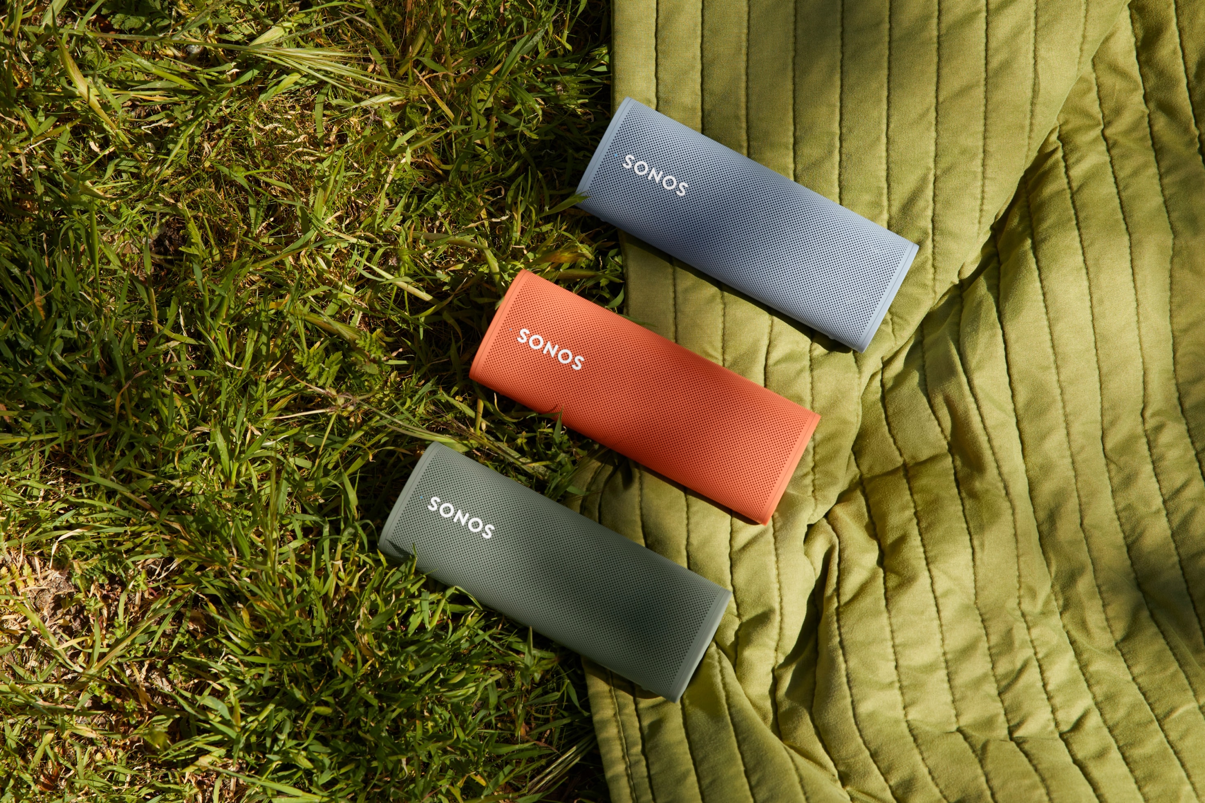 Roam speakers in Olive, Sunset, and Wave on grass