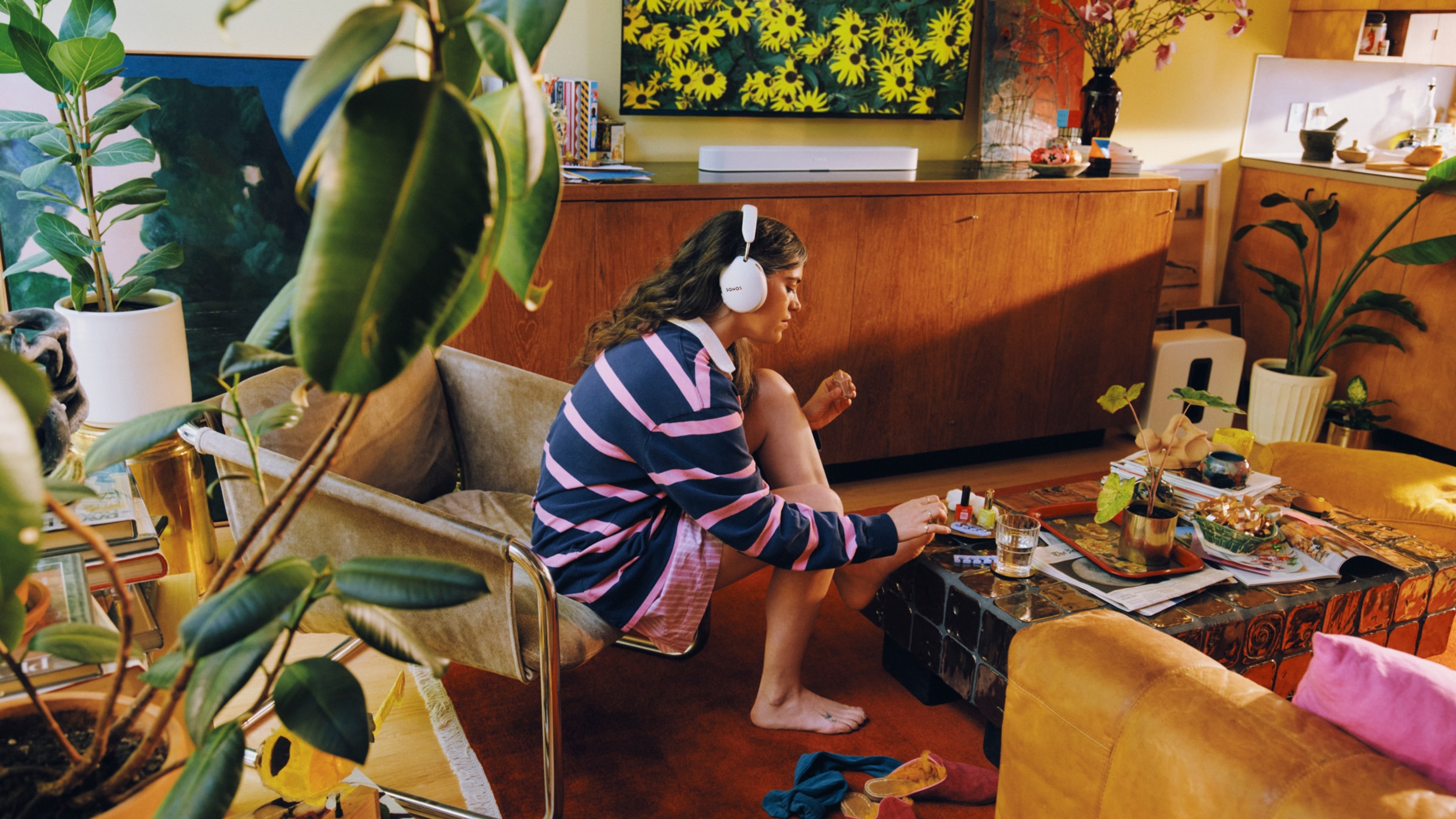 Person wearing a white Sonos Ace Ultra headphones with a white Beam Ultra in the background