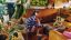 Person wearing white Sonos Ace Ultra headphones sitting in a living room with plants and wooden furniture while painting their nails