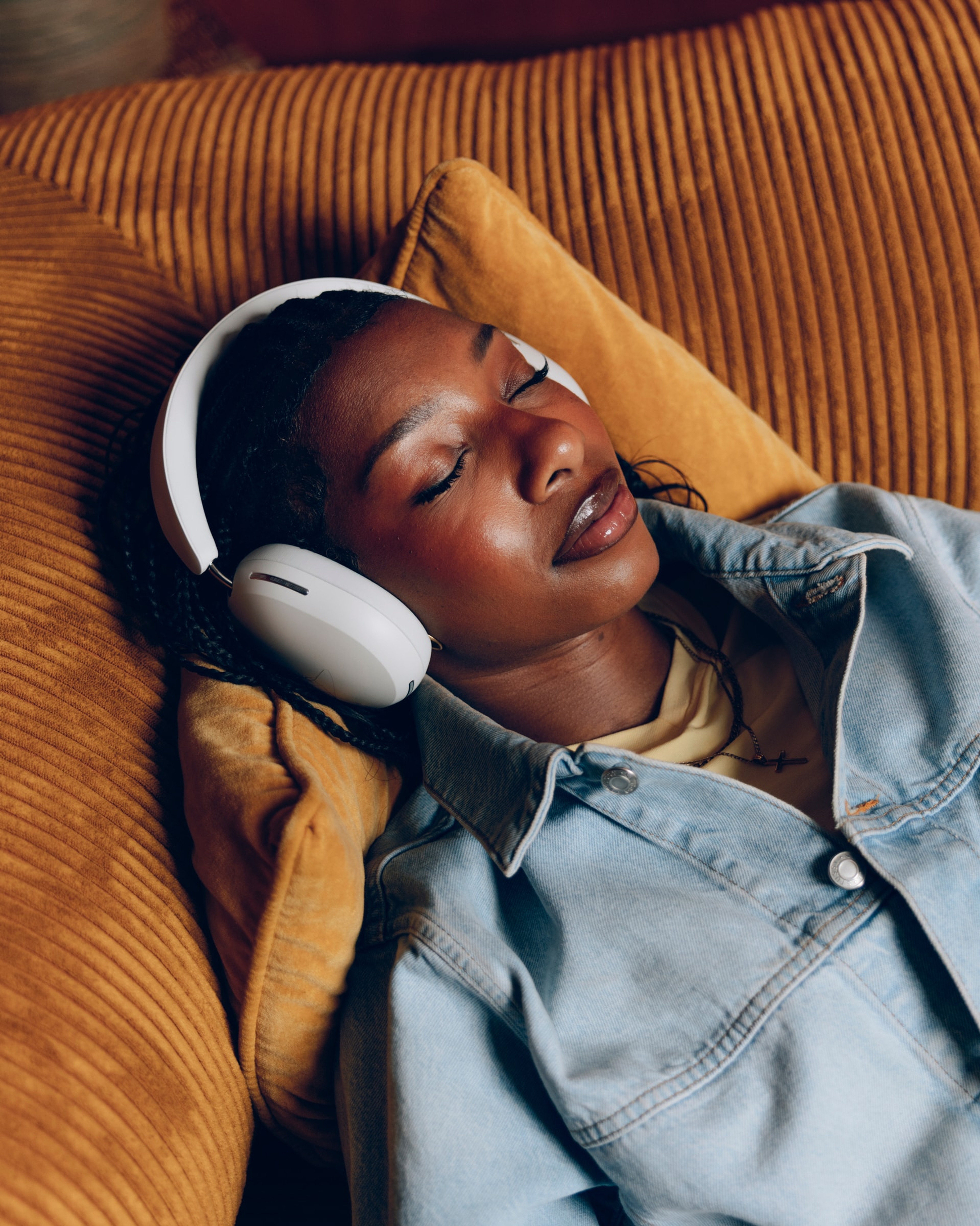 Nia Smith laying on a couch wearing Sonos Ace headphones