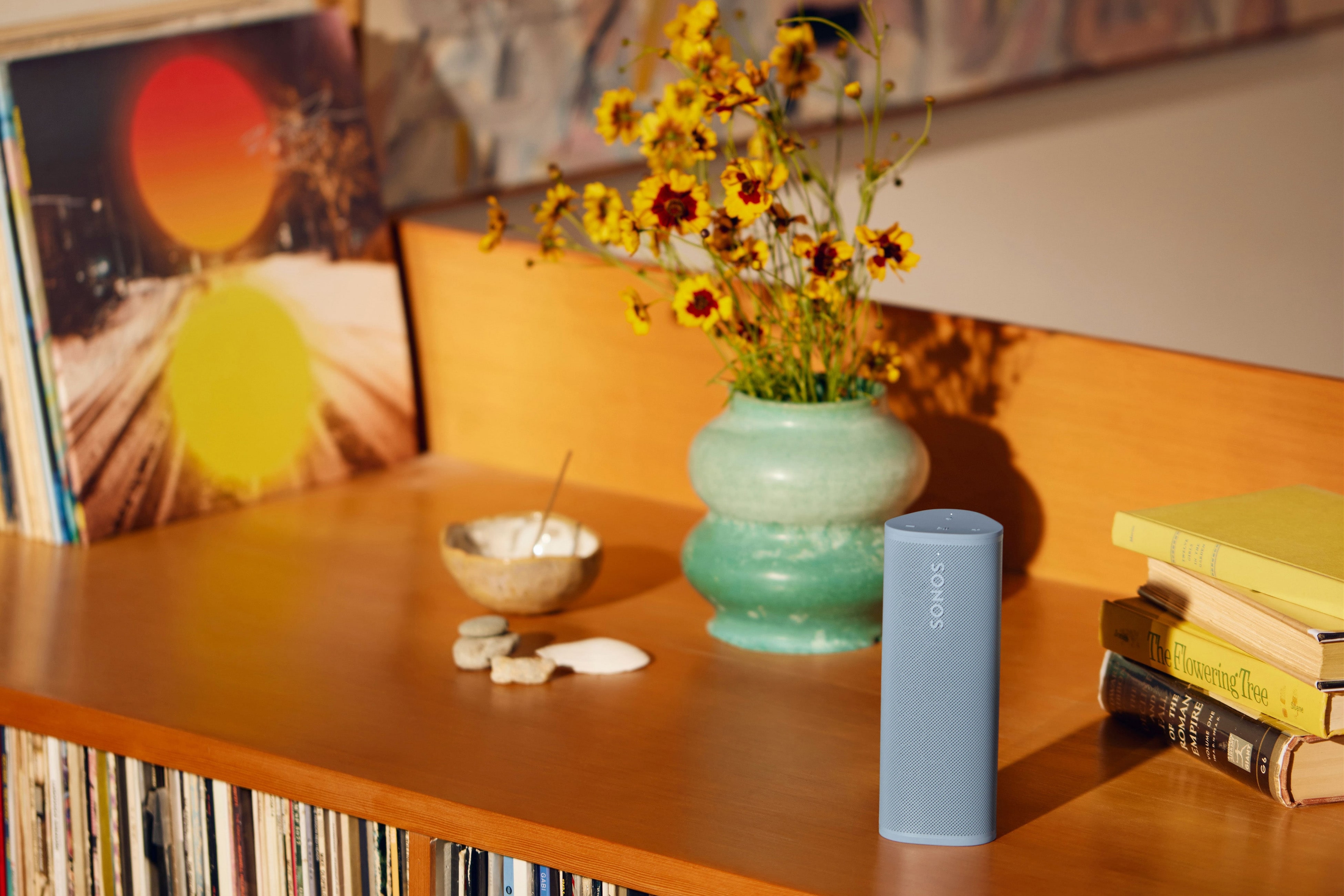 Sonos Roam 2 couleur Wave posé sur une étagère à côté de fleurs dans un vase