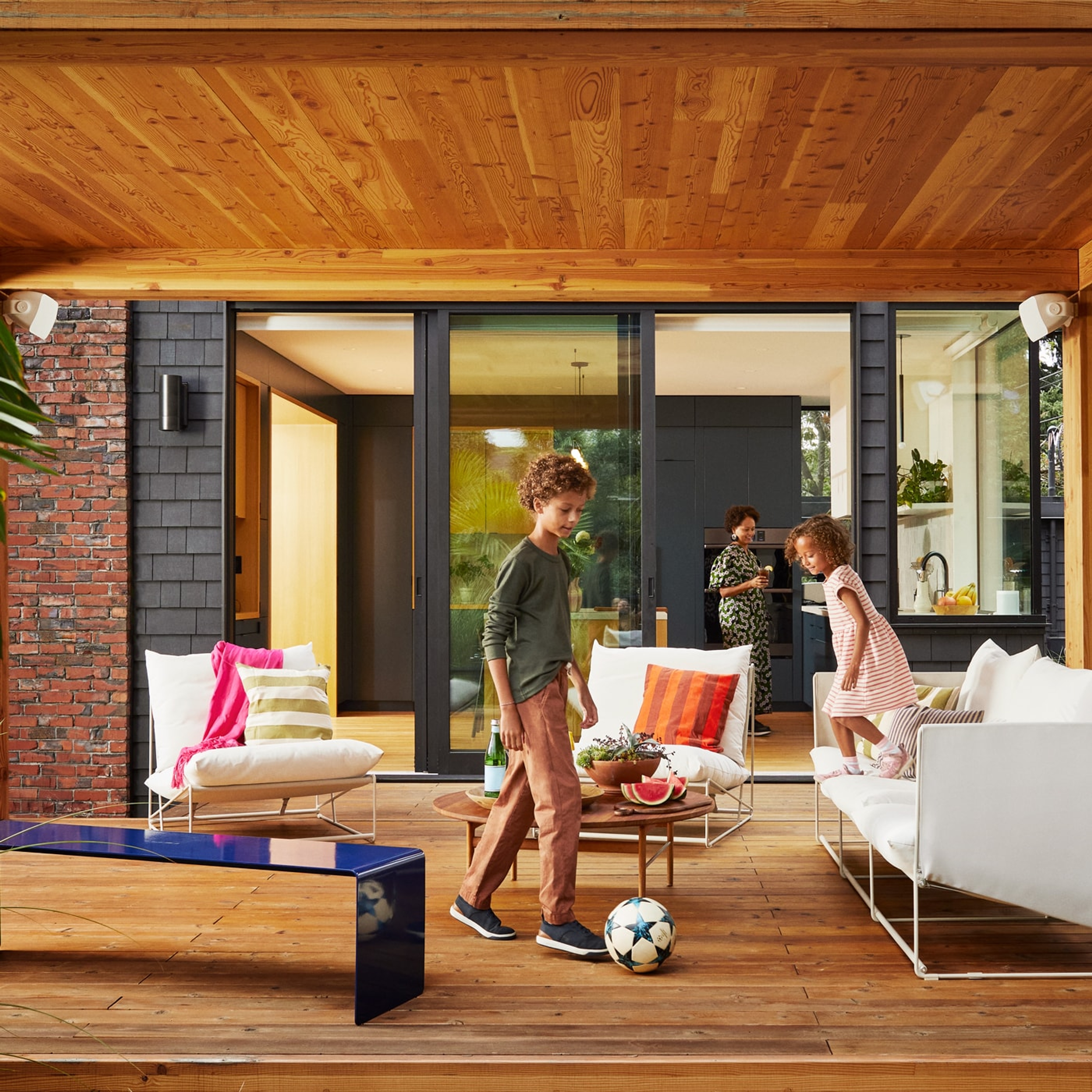 Kids playing with a soccer ball on the patio with outdoor speakers by Sonos and Sonance installed