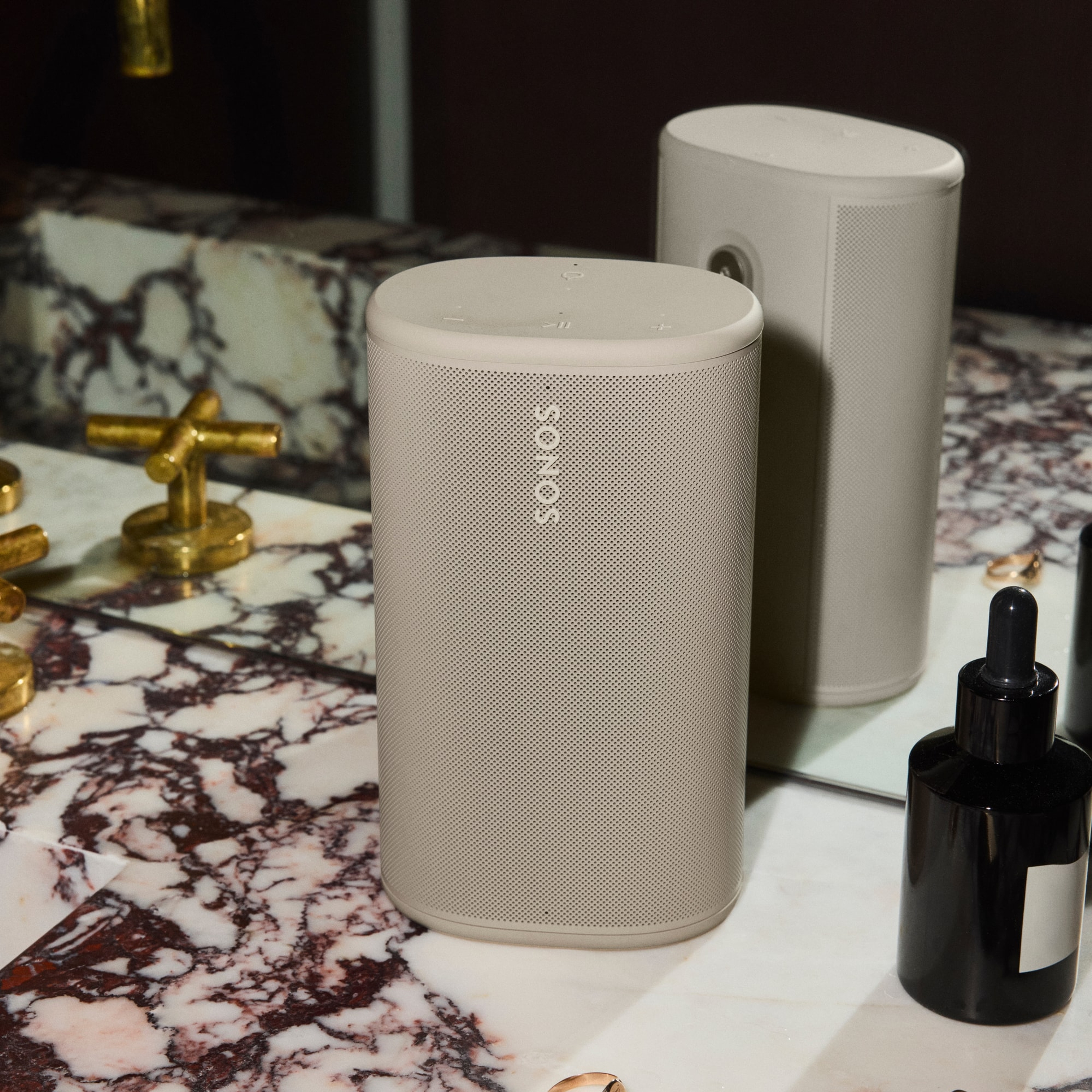 Une personne tendant une enceinte Sonos Play blanche à un ami situé en contrebas, par-dessus un balcon