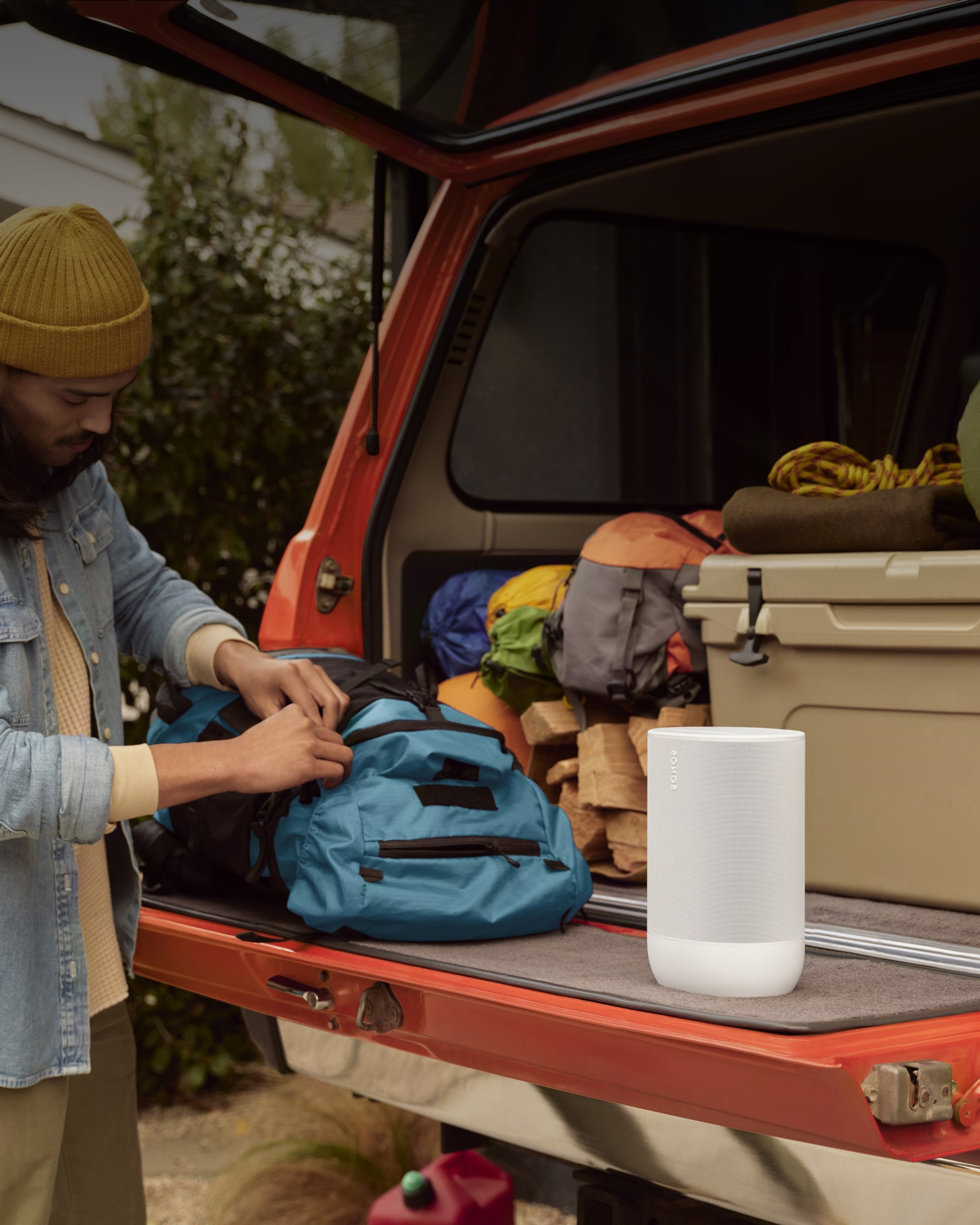 User packing up their truck for camping with a white Move 2 portable speaker
