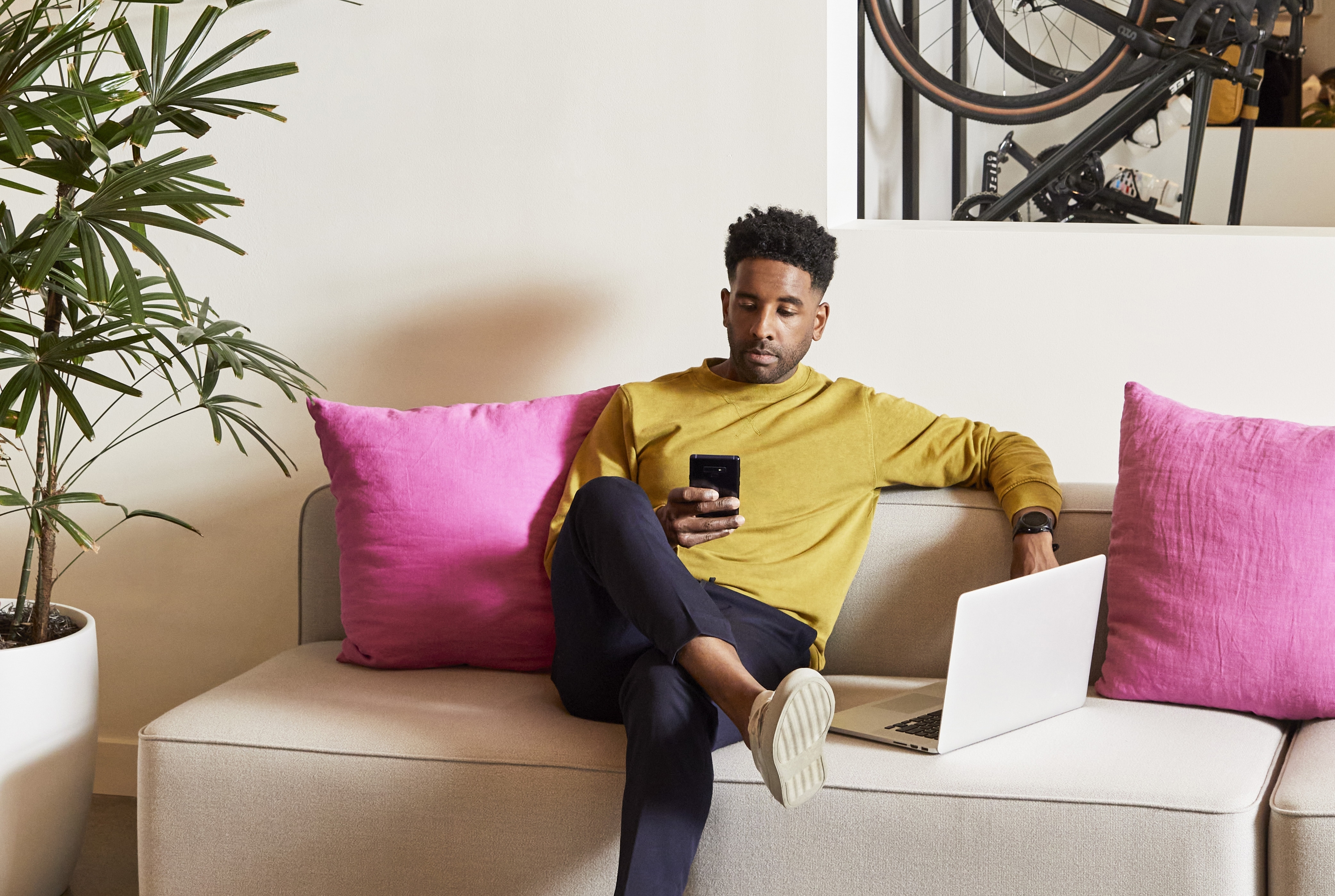 Person on the couch with phone and laptop