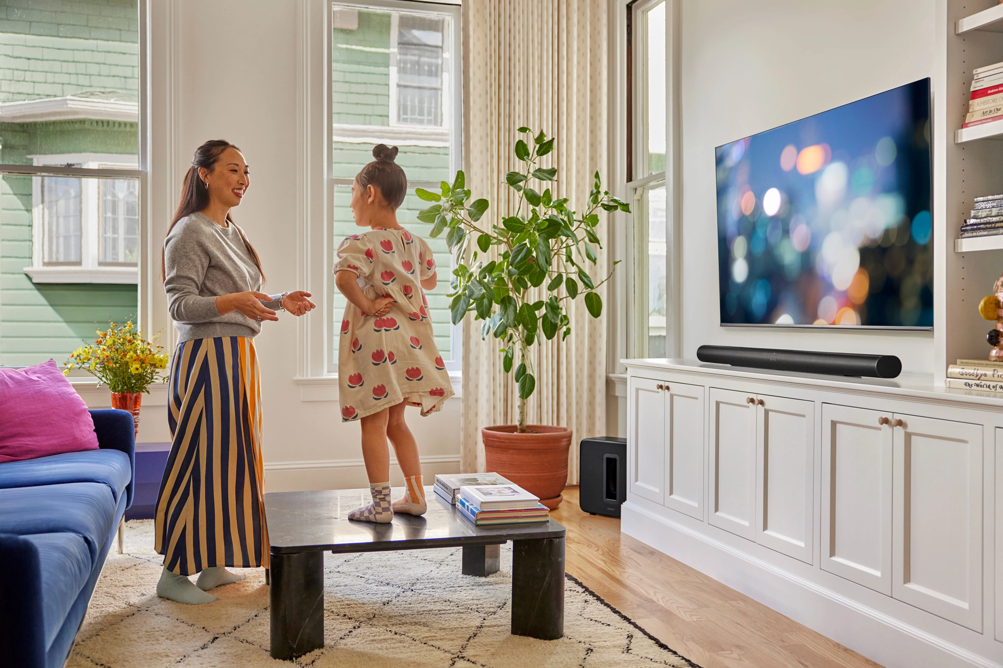 Mamma och dotter som lyssnar på Sonos Radio på en svart Arc Ultra i vardagsrummet