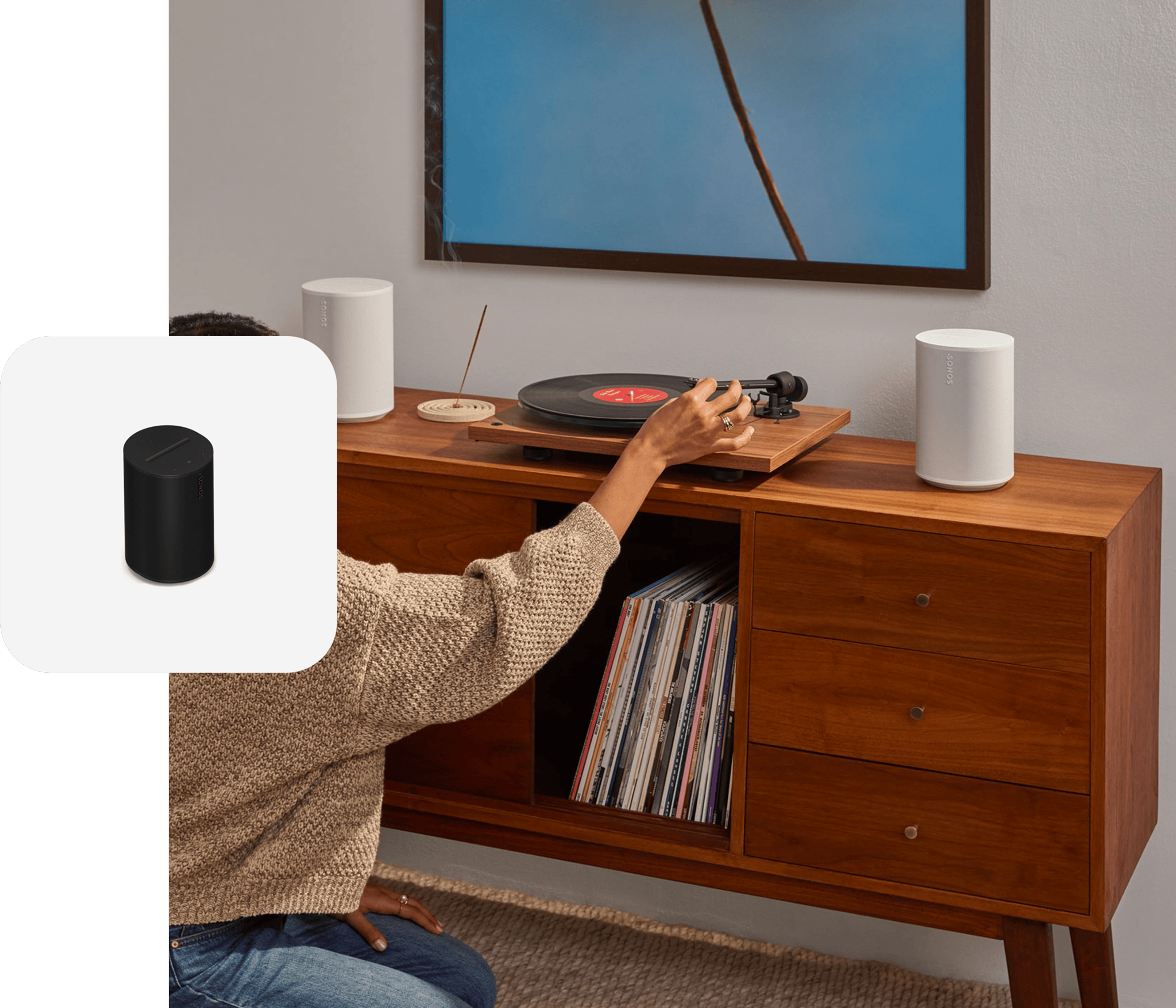 A pair of white Sonos Era 100 SL speakers connected to a turntable while someone drops the needle on a vinyl record