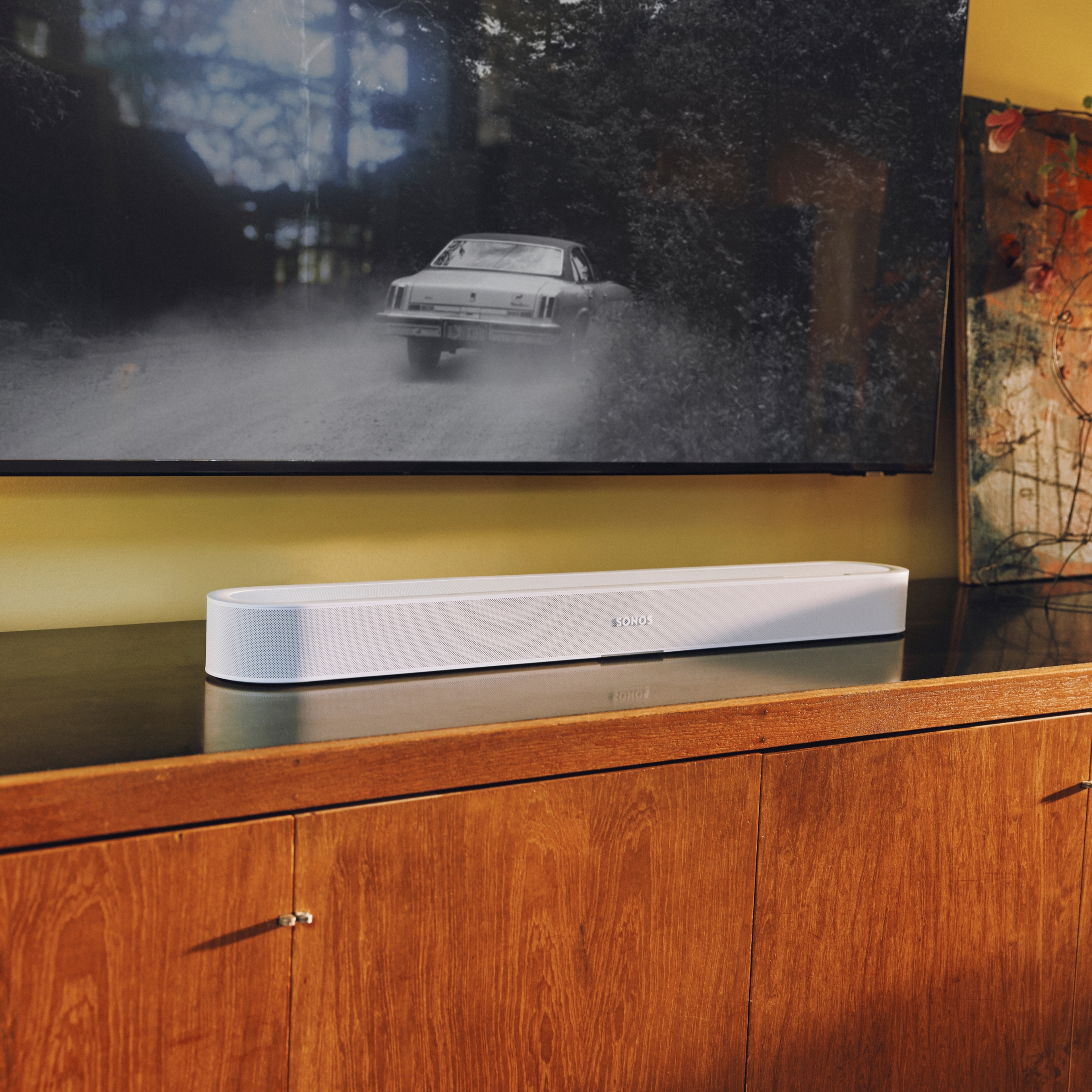 A white Sonos Beam Ultra soundbar on wooden TV stand