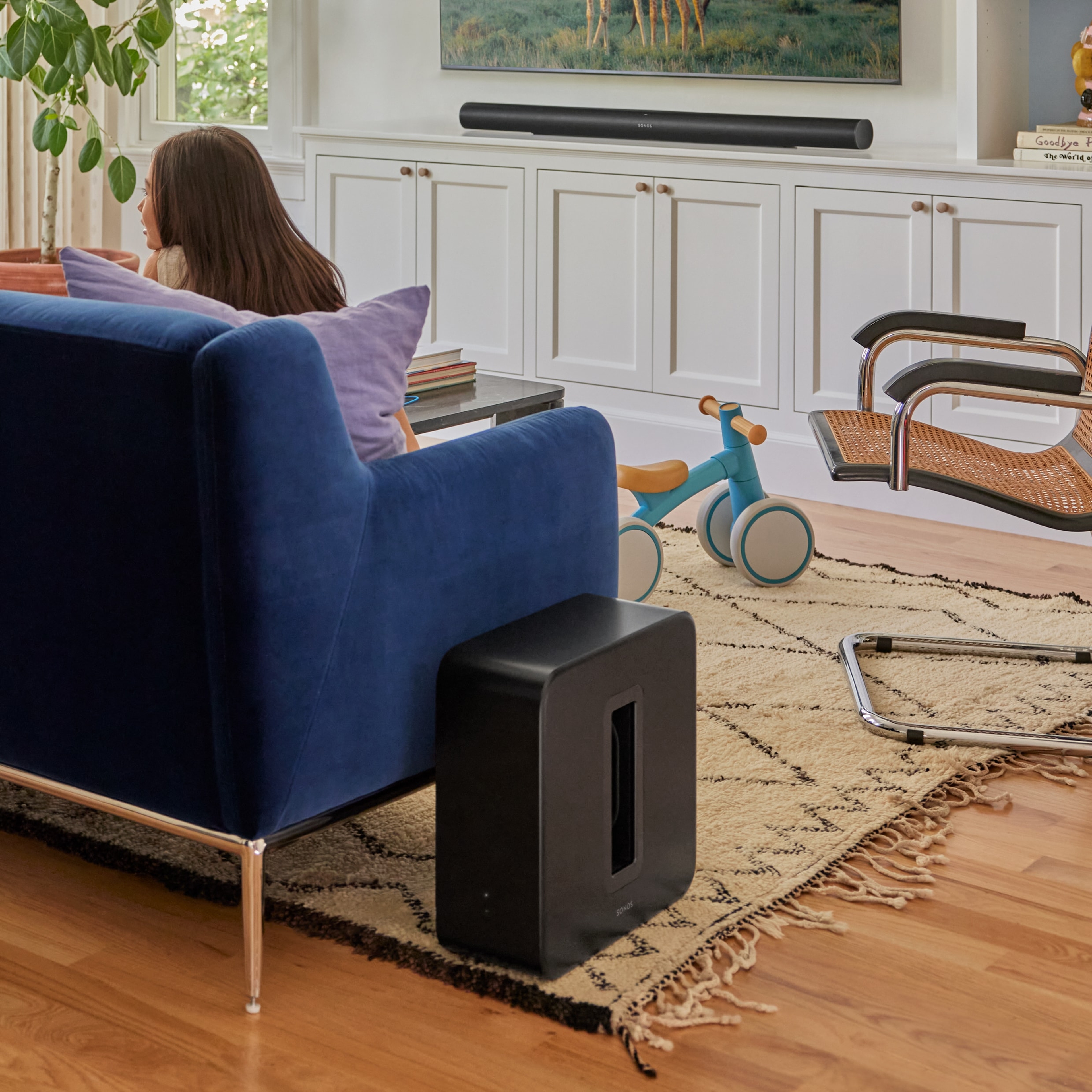 Un Sonos Sub 4 à côté d'un canapé dans un salon, utilisé avec une Sonos Arc Ultra