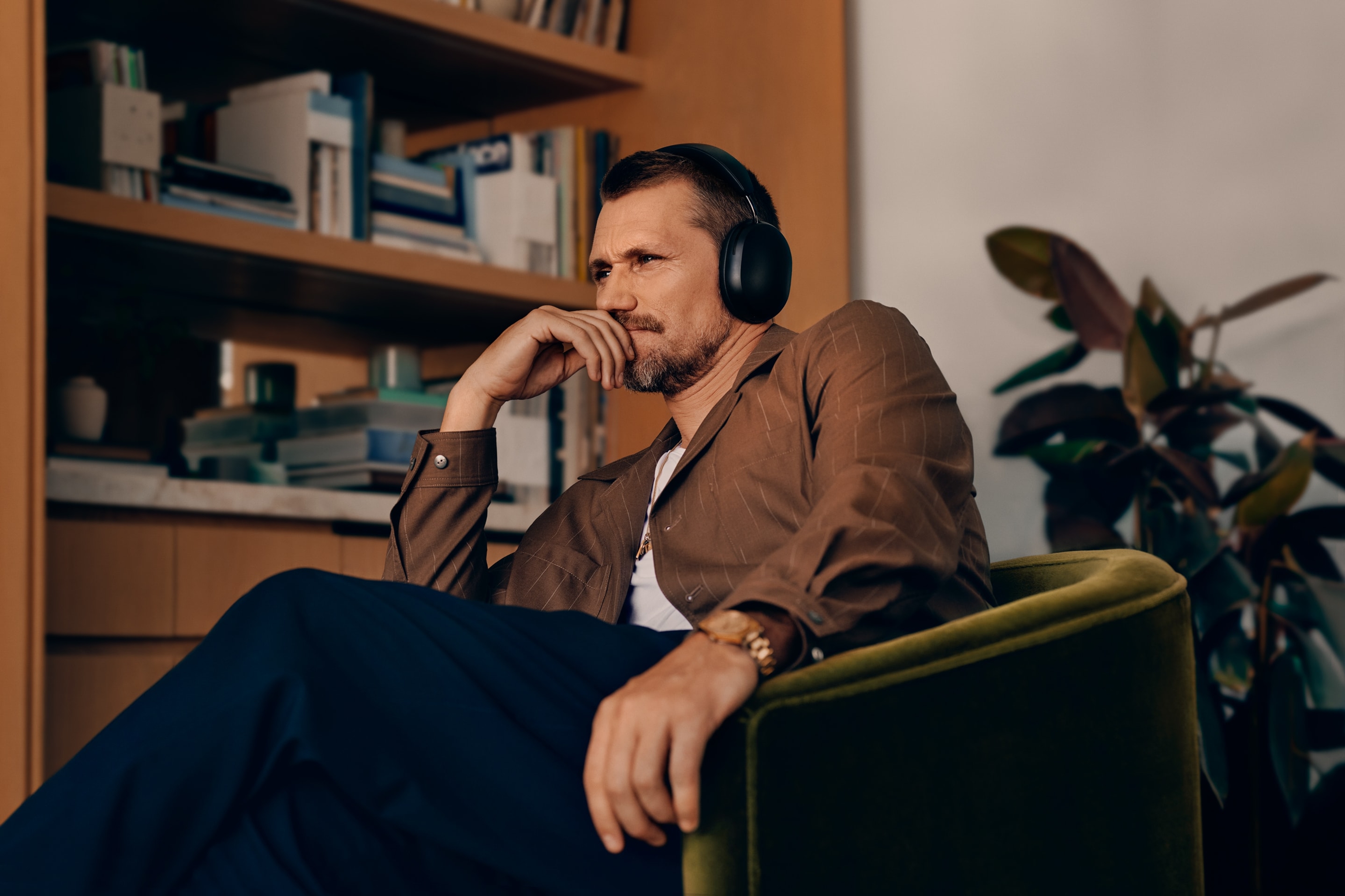 Mann som har på et par svarte Sonos Ace-hodetelefoner mens han sitter i en stol