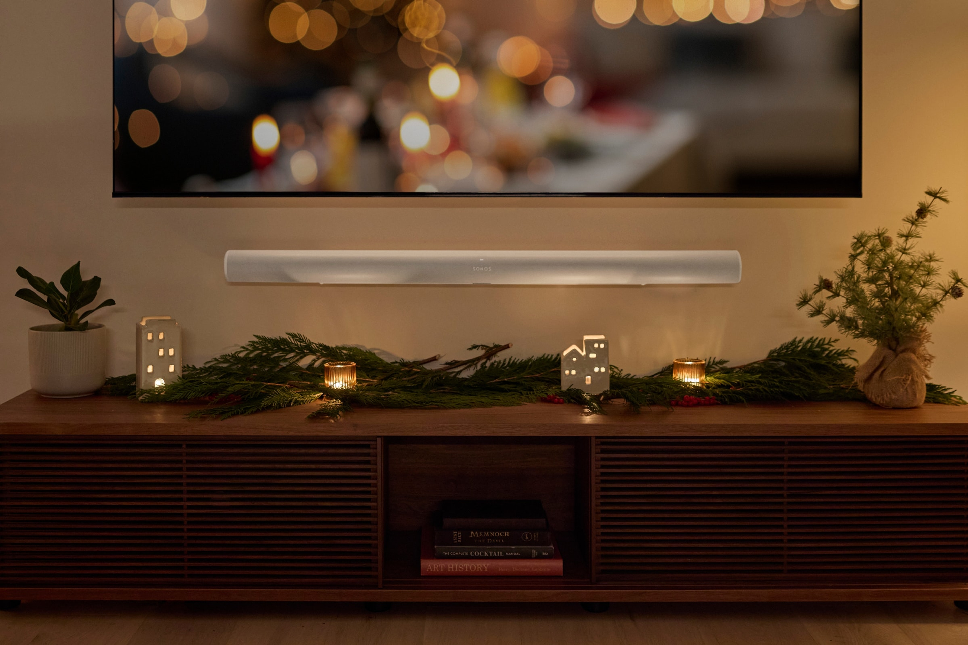 放在挂有节日花环的餐具柜上方的壁挂式白色Sonos Arc Ultra