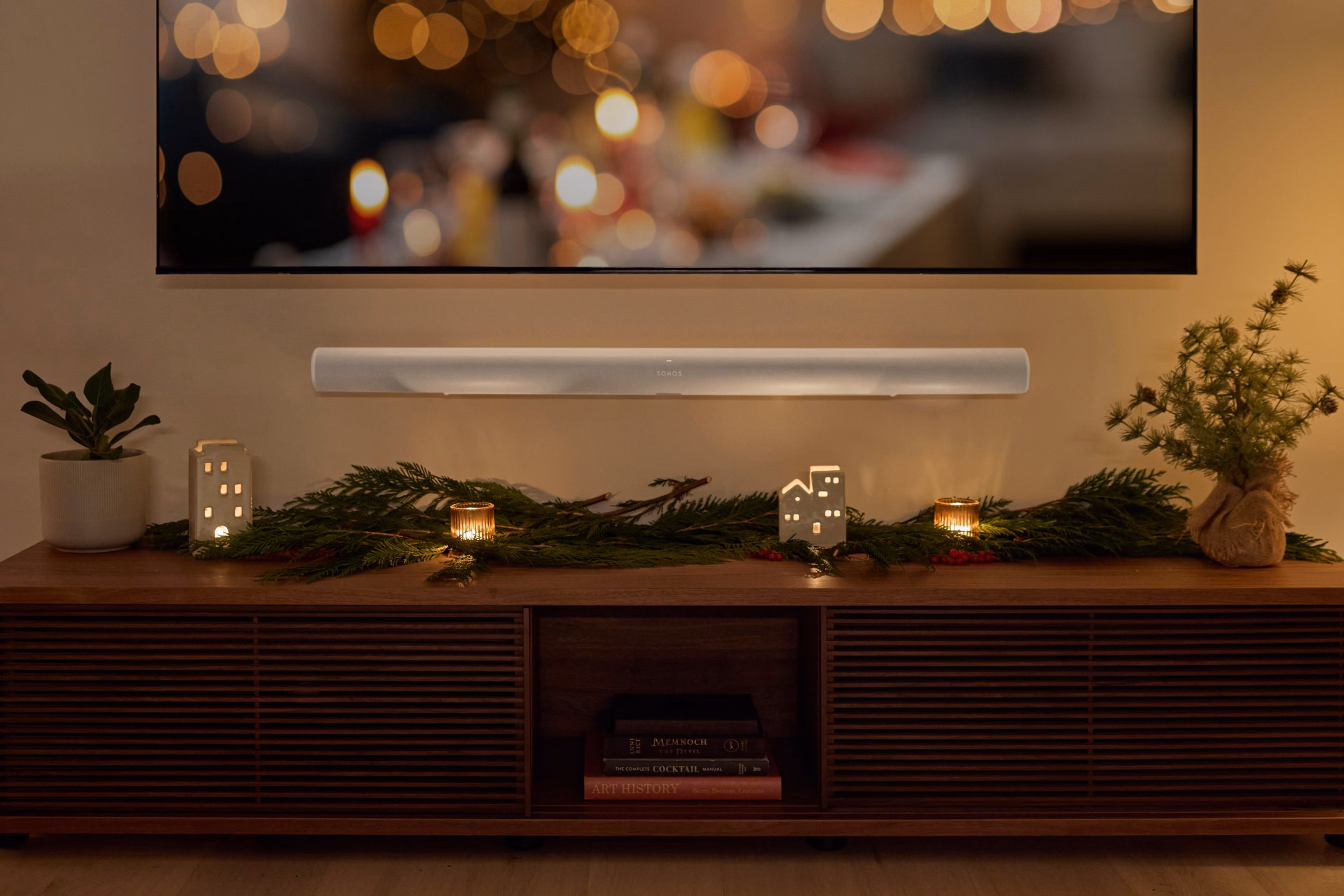 放在挂有节日花环的餐具柜上方的壁挂式白色Sonos Arc Ultra