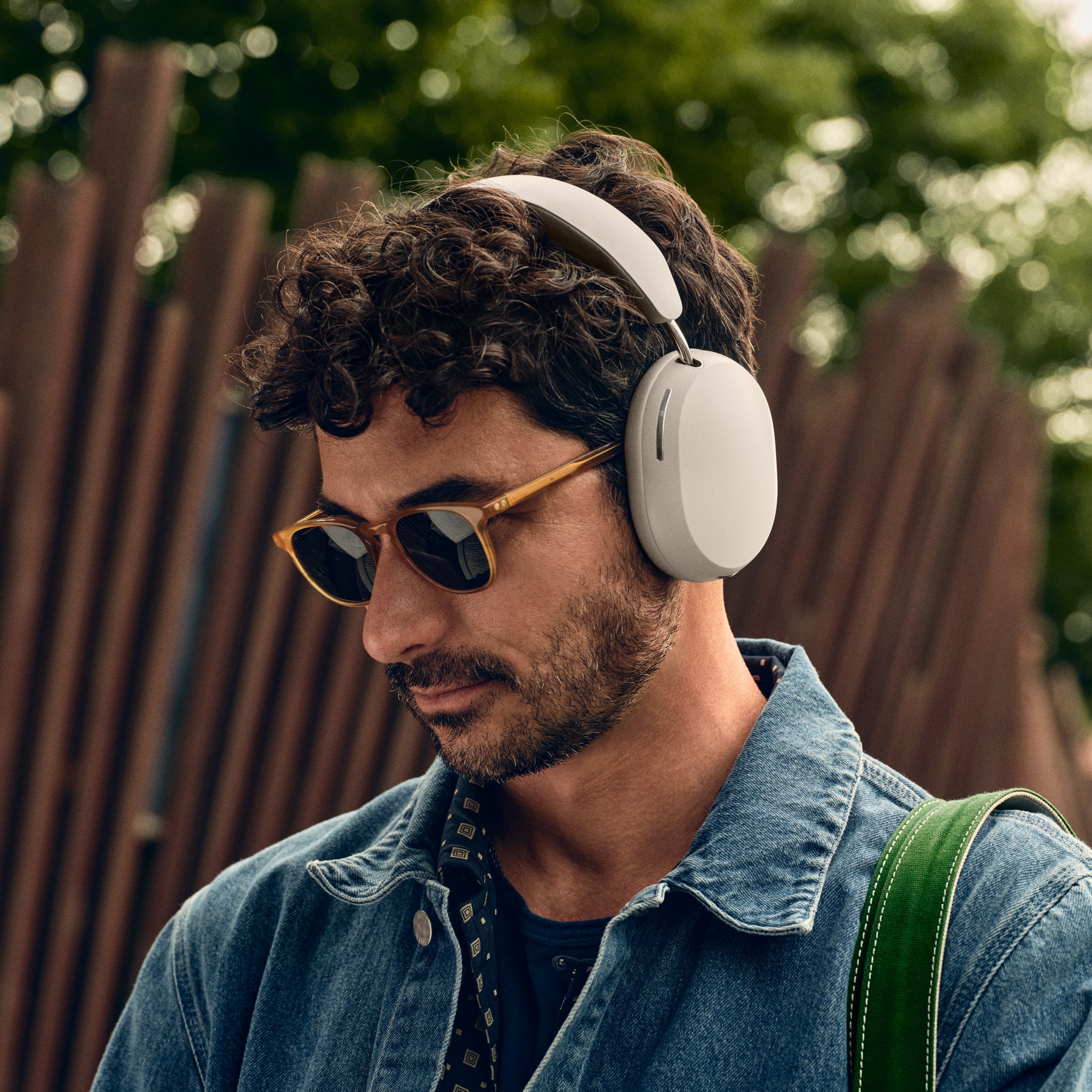 Une personne écoutant de la musique avec un casque audio Sonos Ace blanc devant un café