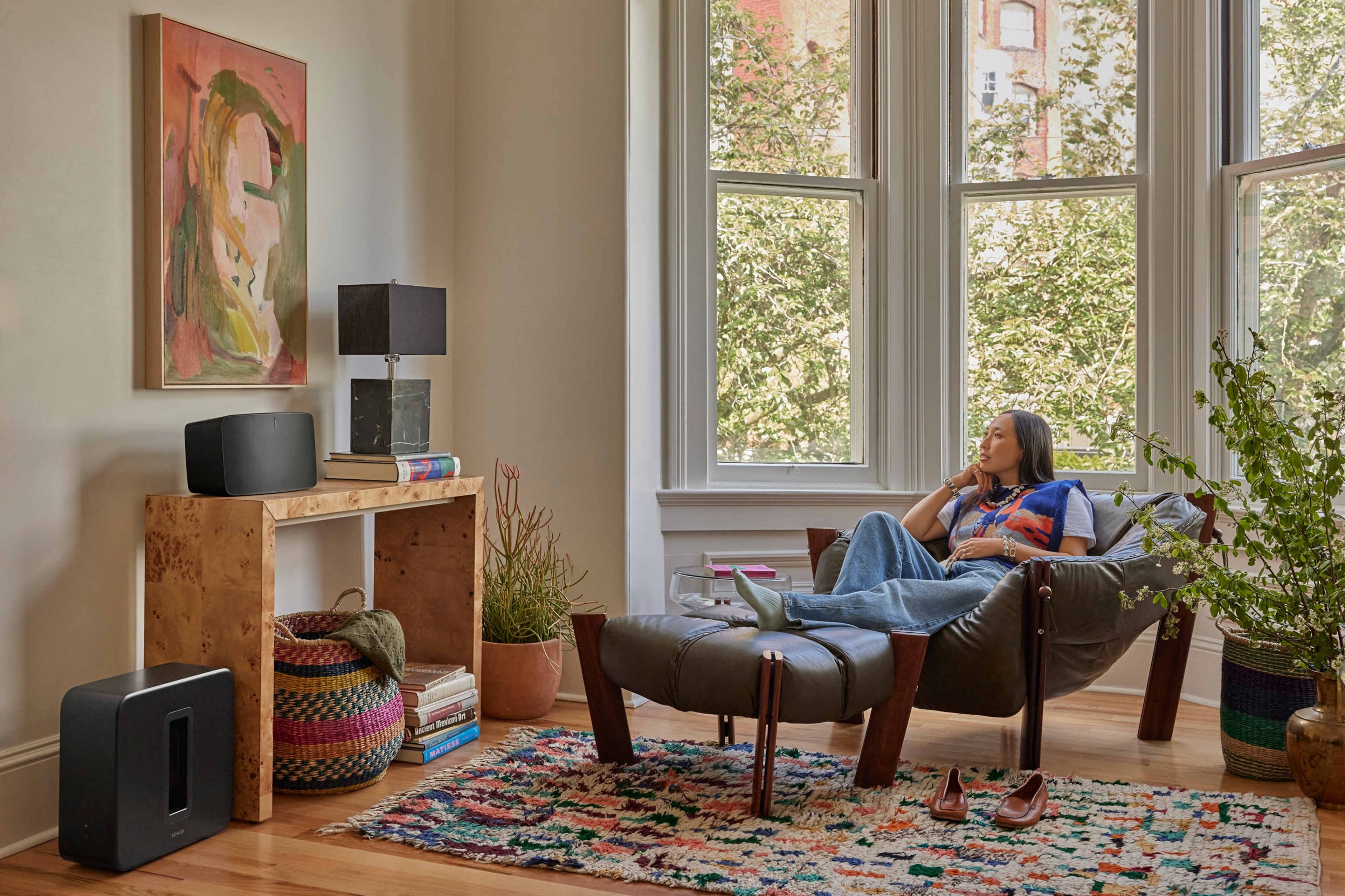 Una persona sentada en una silla escuchando música con un Sonos Five y un Sub 4