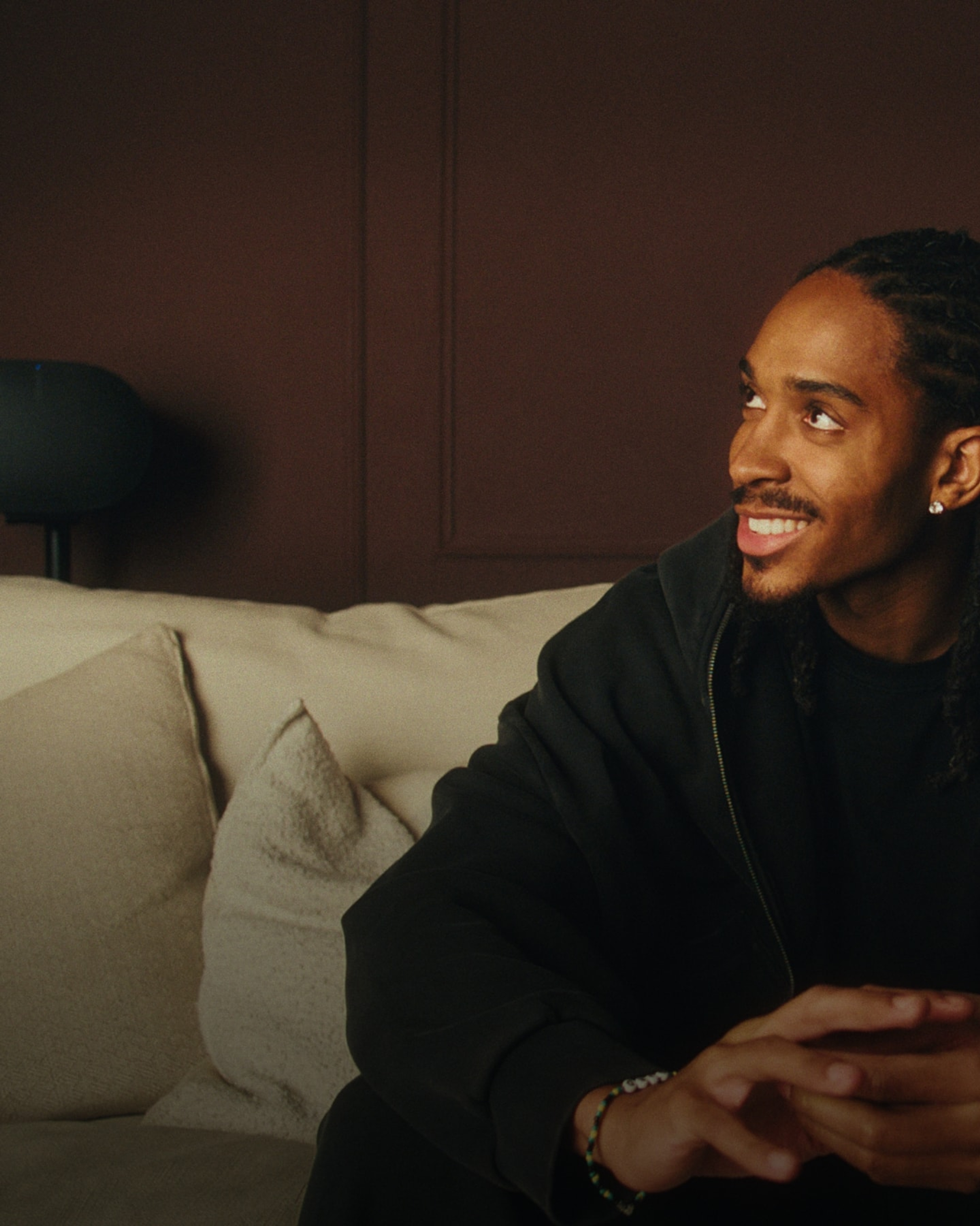 English footballer Djed Spence listening to a pair of black Sonos Era 300 speakers in his home