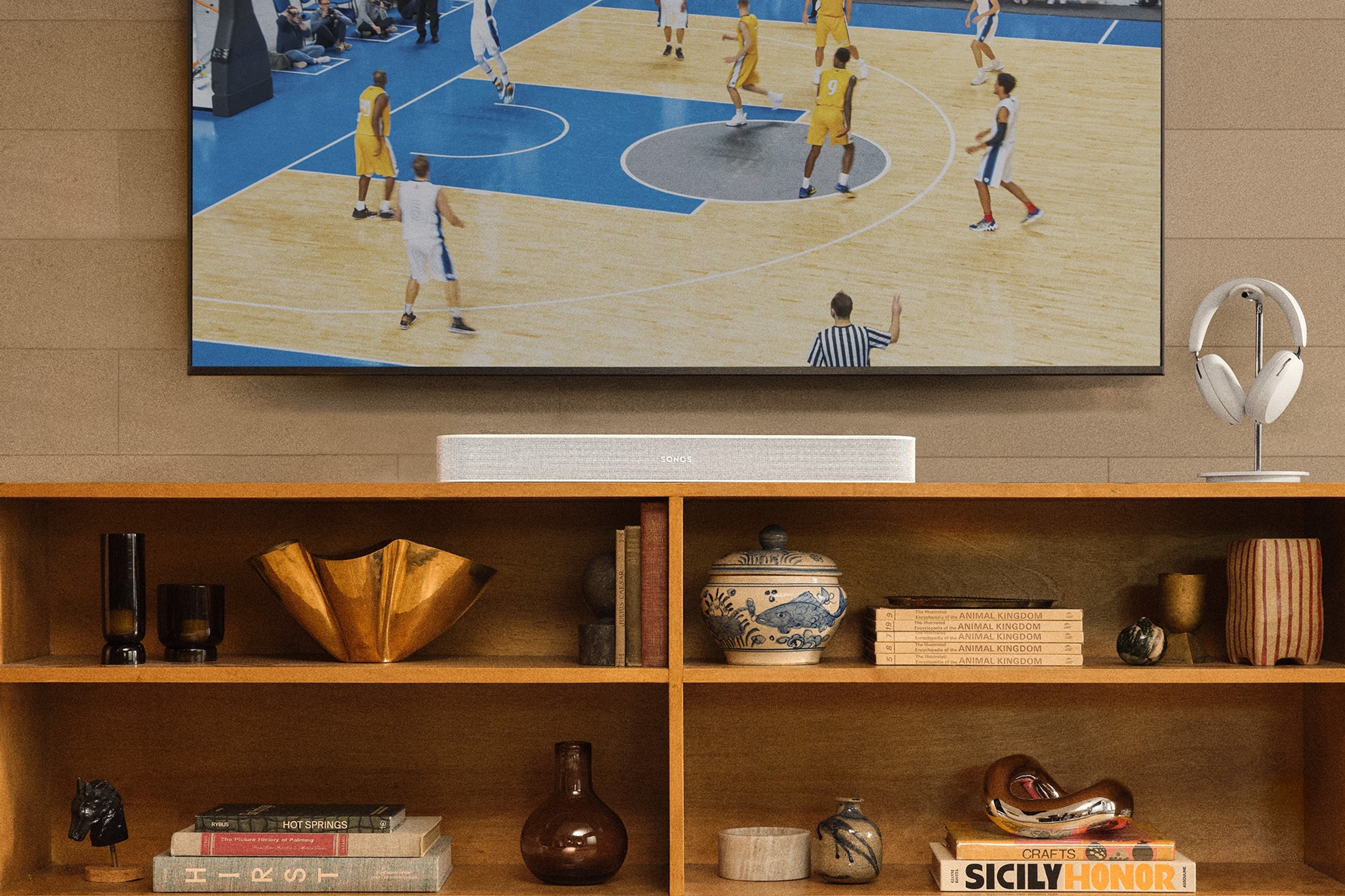 Sonos Beam blanche et Sonos Ace blancs près d’un téléviseur sur lequel on voit une partie de basketball