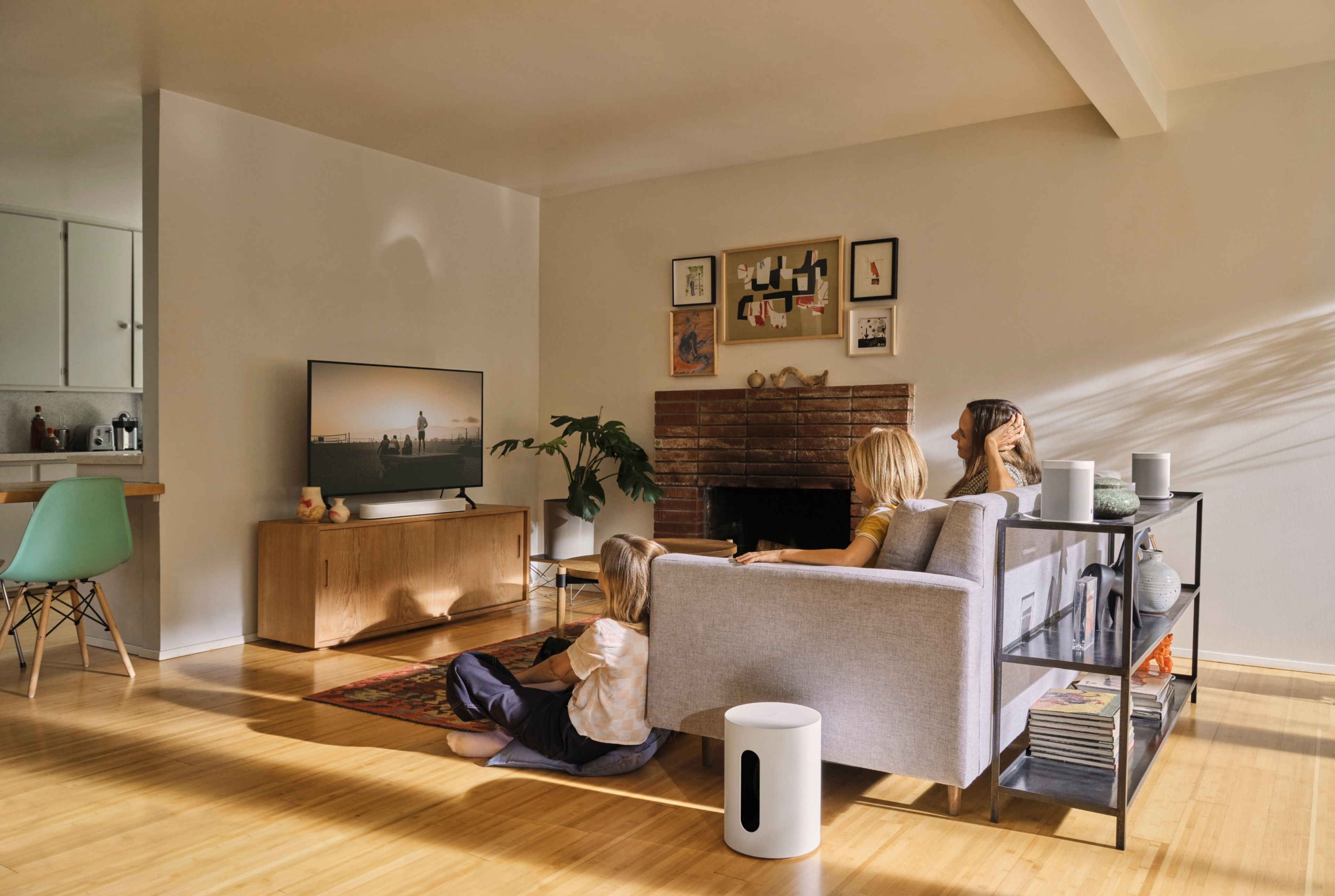 A black Sonos Sub Mini placed next to a modern sofa