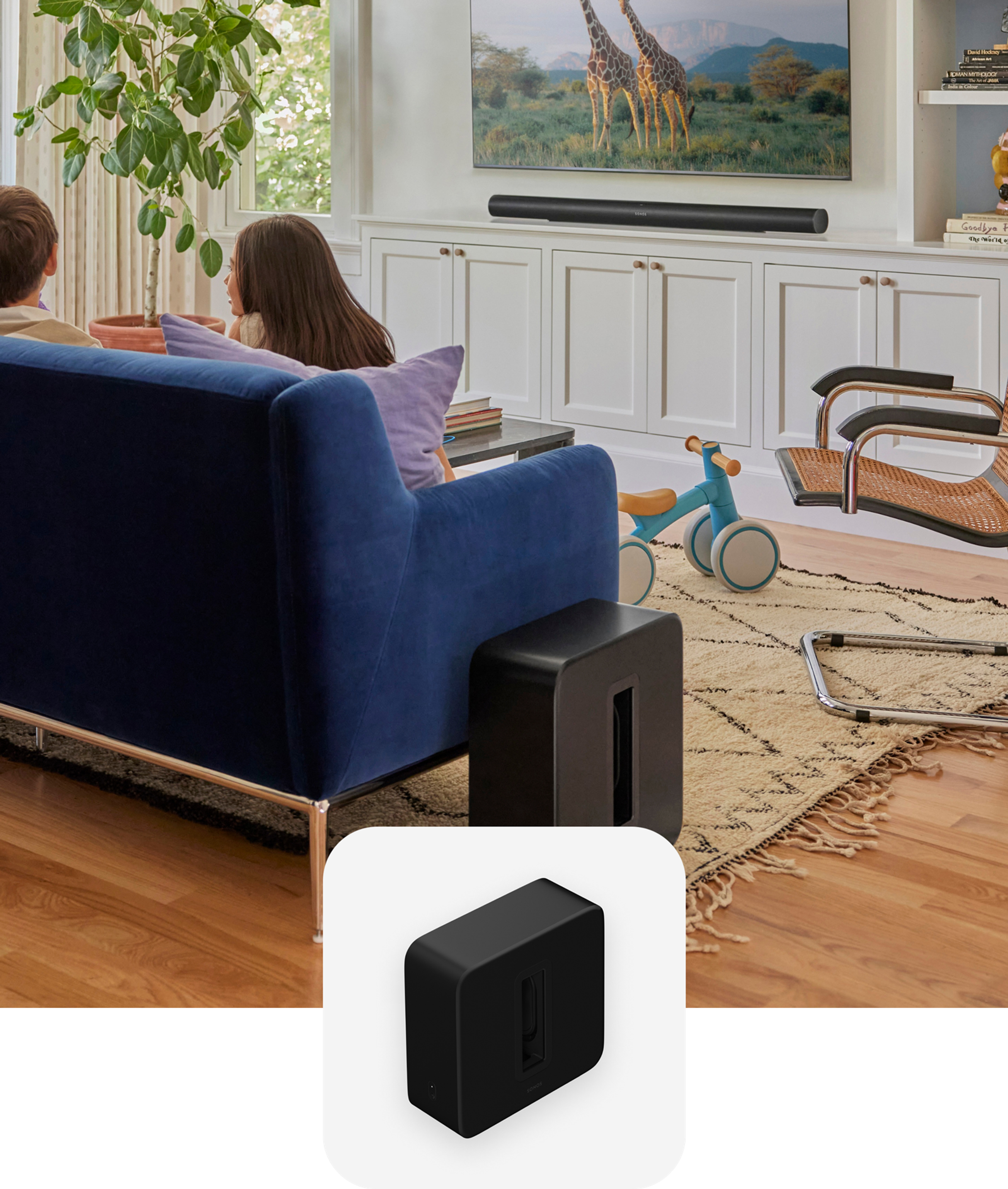 Kids sitting on a blue couch in the living room with black Sonos Sub 4 and Arc Ultra and a black Sub 4 product tile overlay