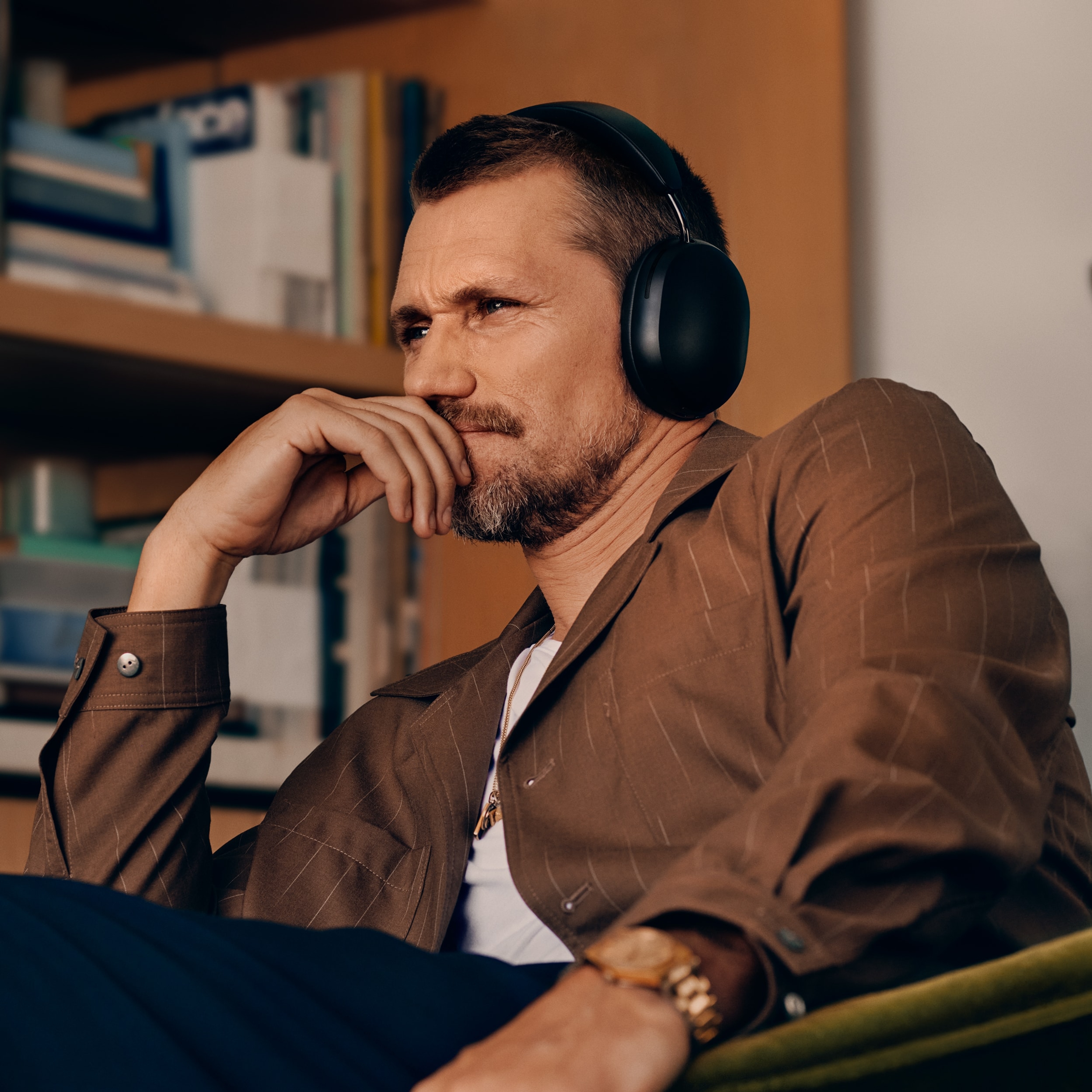 Mies käyttämässä mustia Sonos Ace -kuulokkeita ja istumassa tuolilla