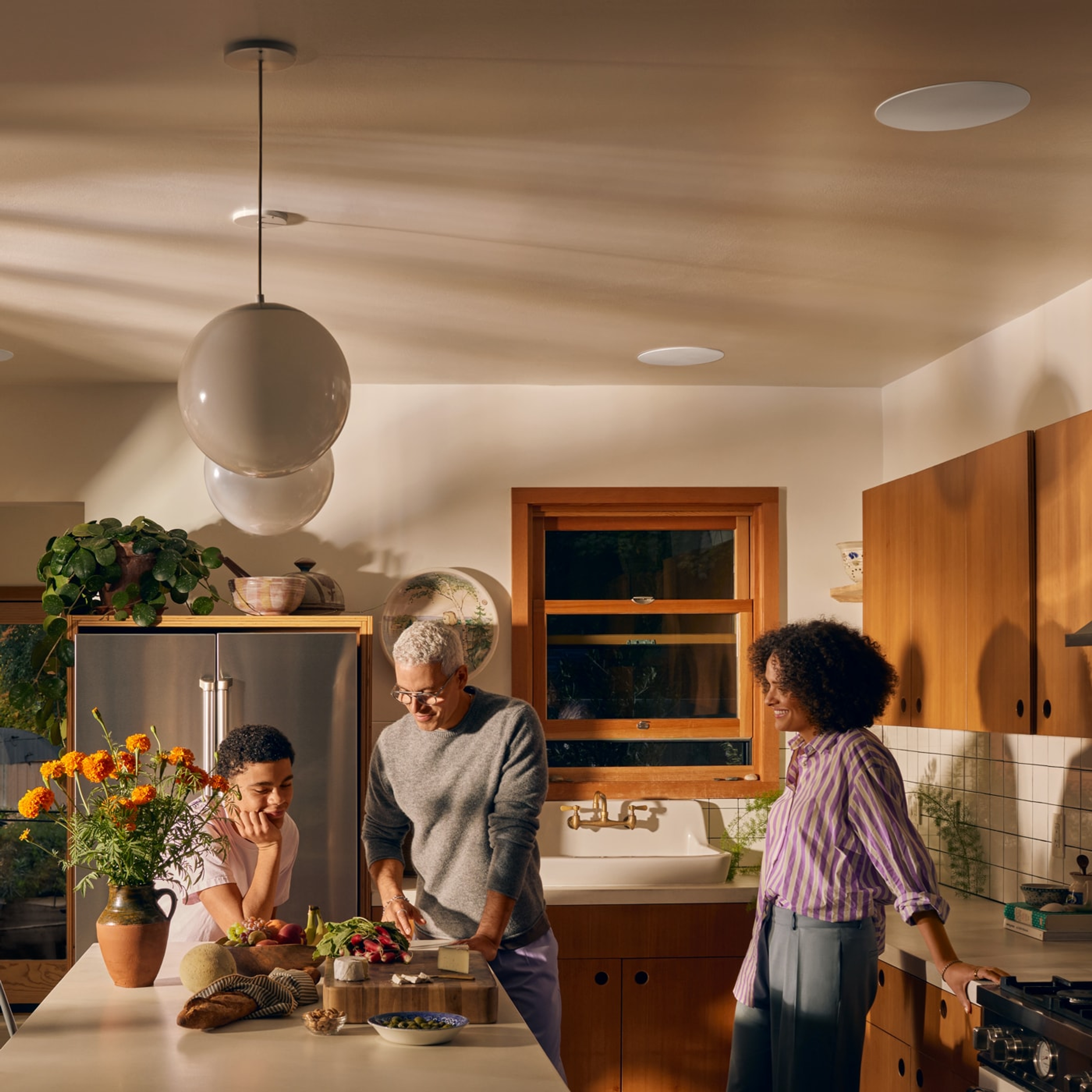 一家人正在烹饪,厨房中安装着吊顶式音响