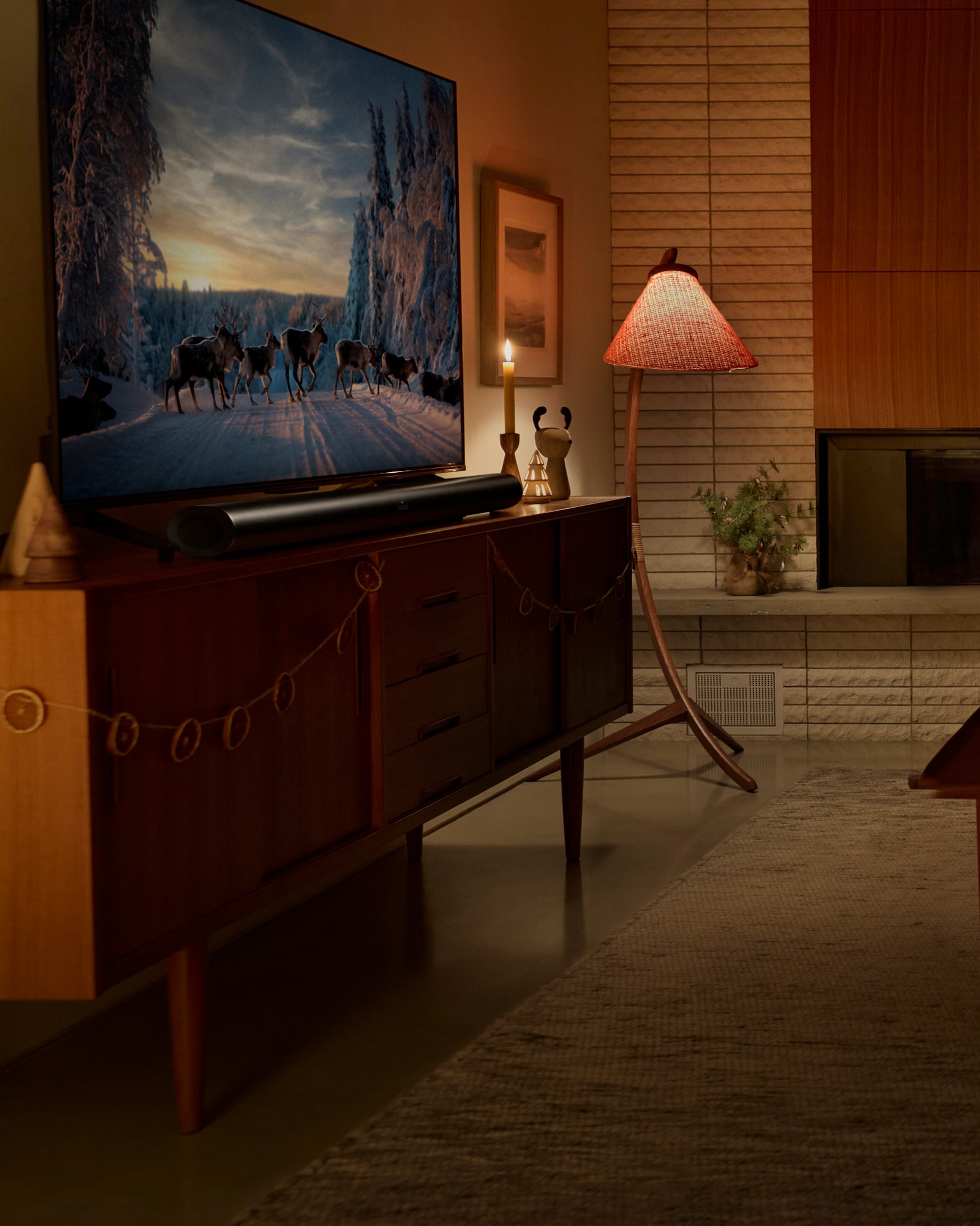 Une famille assiste sur un canapé dans le salon en train de regarder un film des Fêtes avec un système de cinéma maison Sonos Arc Ultra