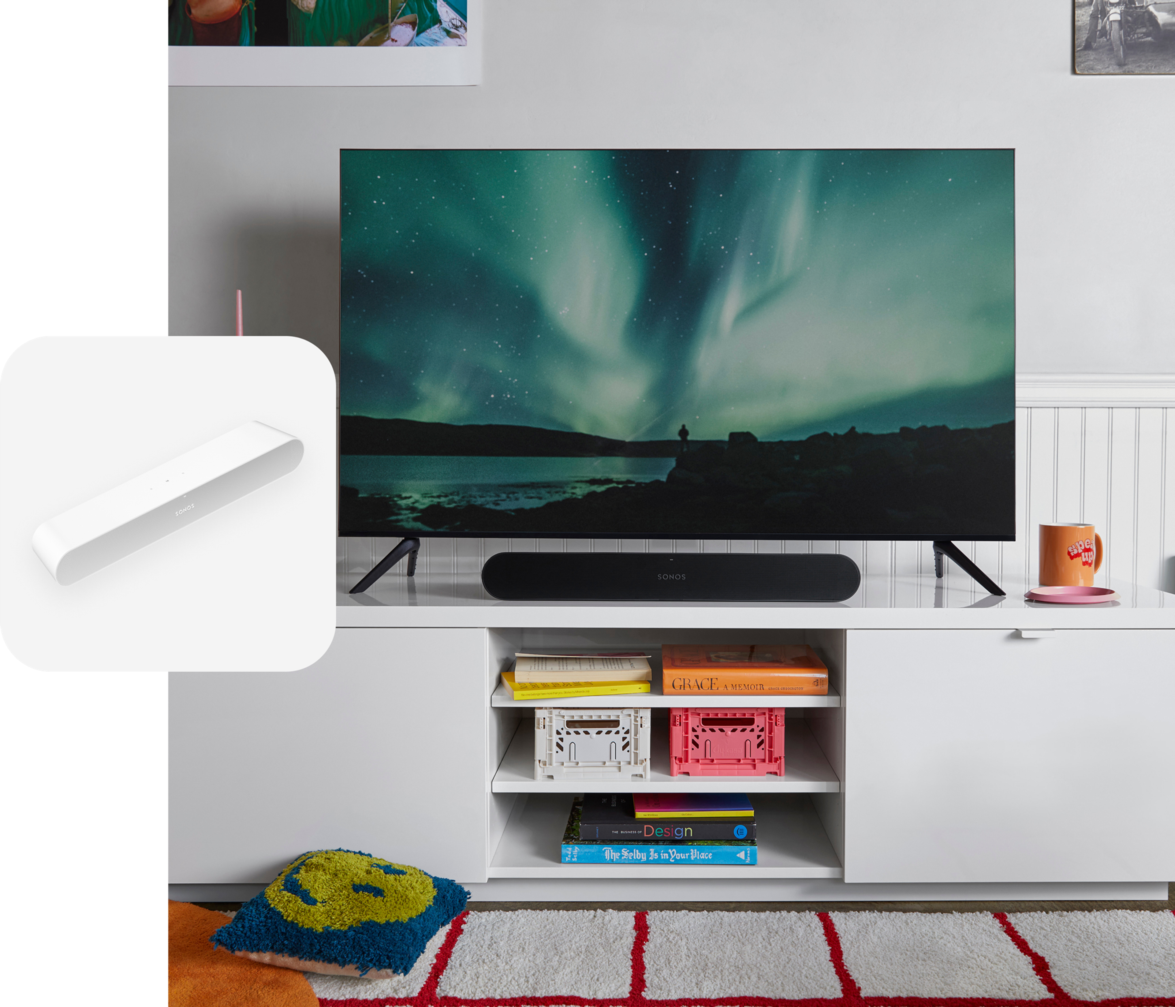 A black Sonos Ray soundbar sitting on a white media console below a TV