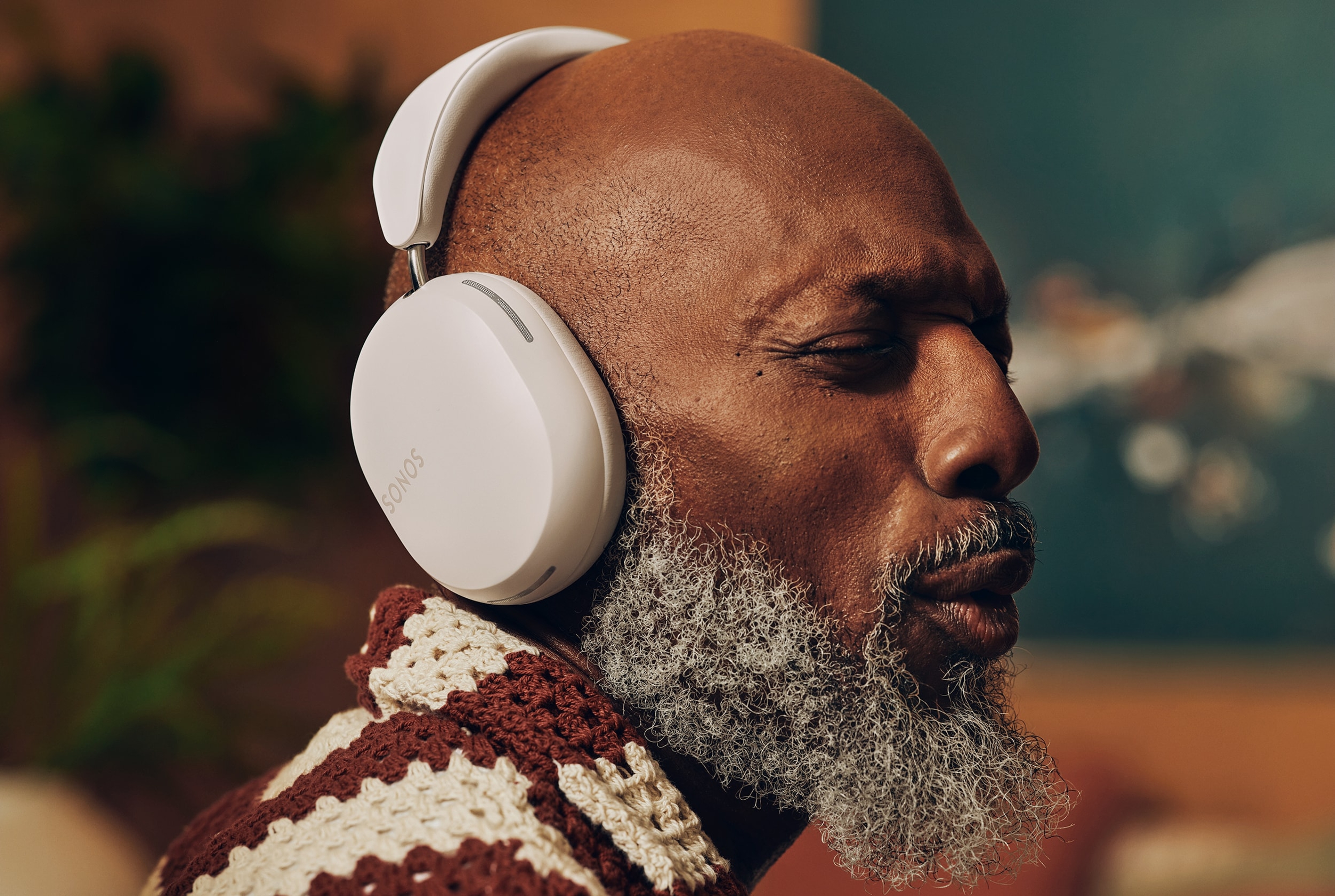 Man die luistert naar muziek op een witte Sonos Ace koptelefoon
