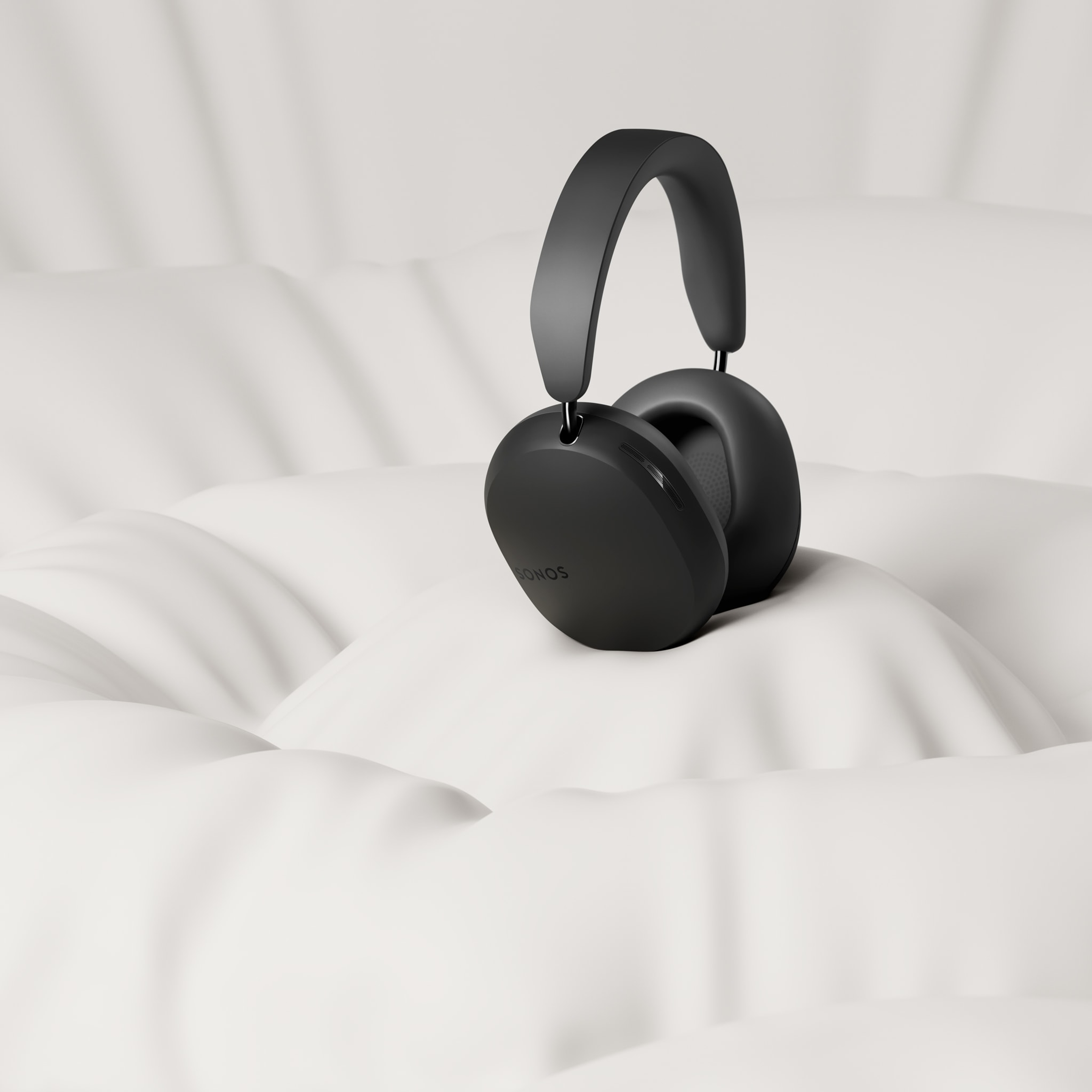 A pair of black Sonos Ace headphones on a pillowy white background