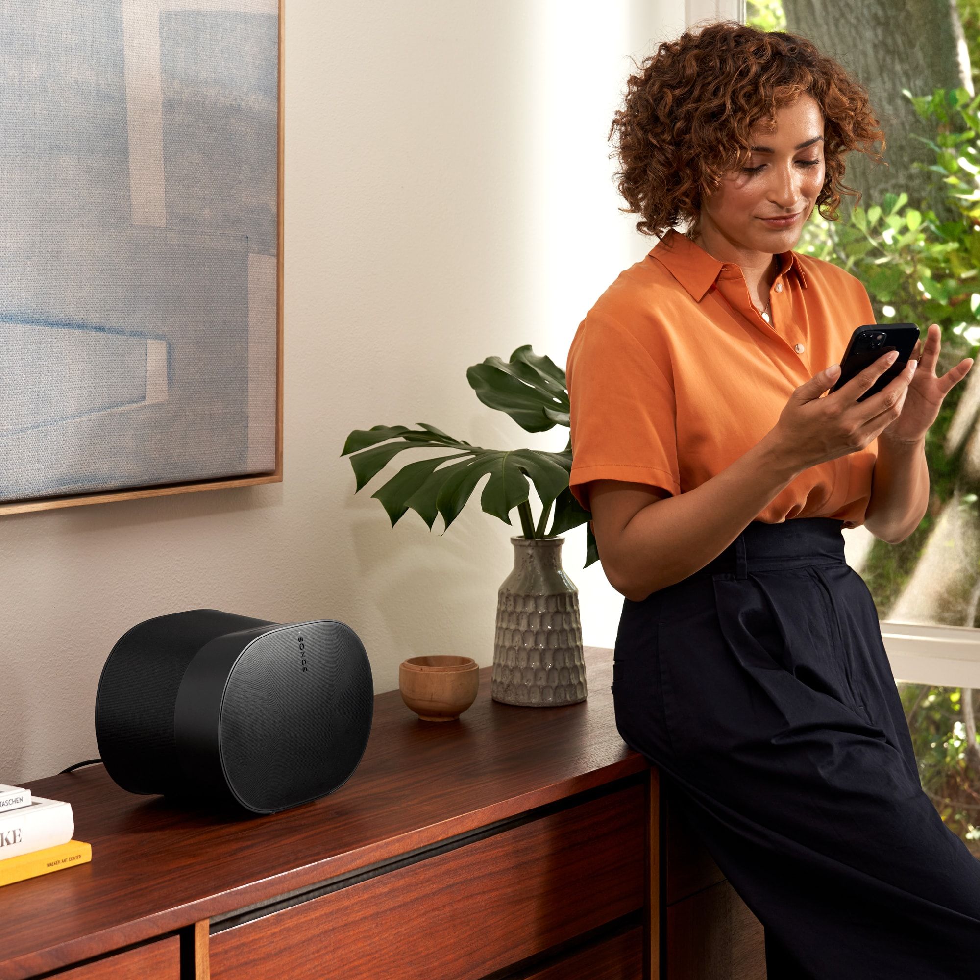 Sonos Era 300 v černé barvě doma, ovládání přes Sonos aplikaci v telefonu z gauče
