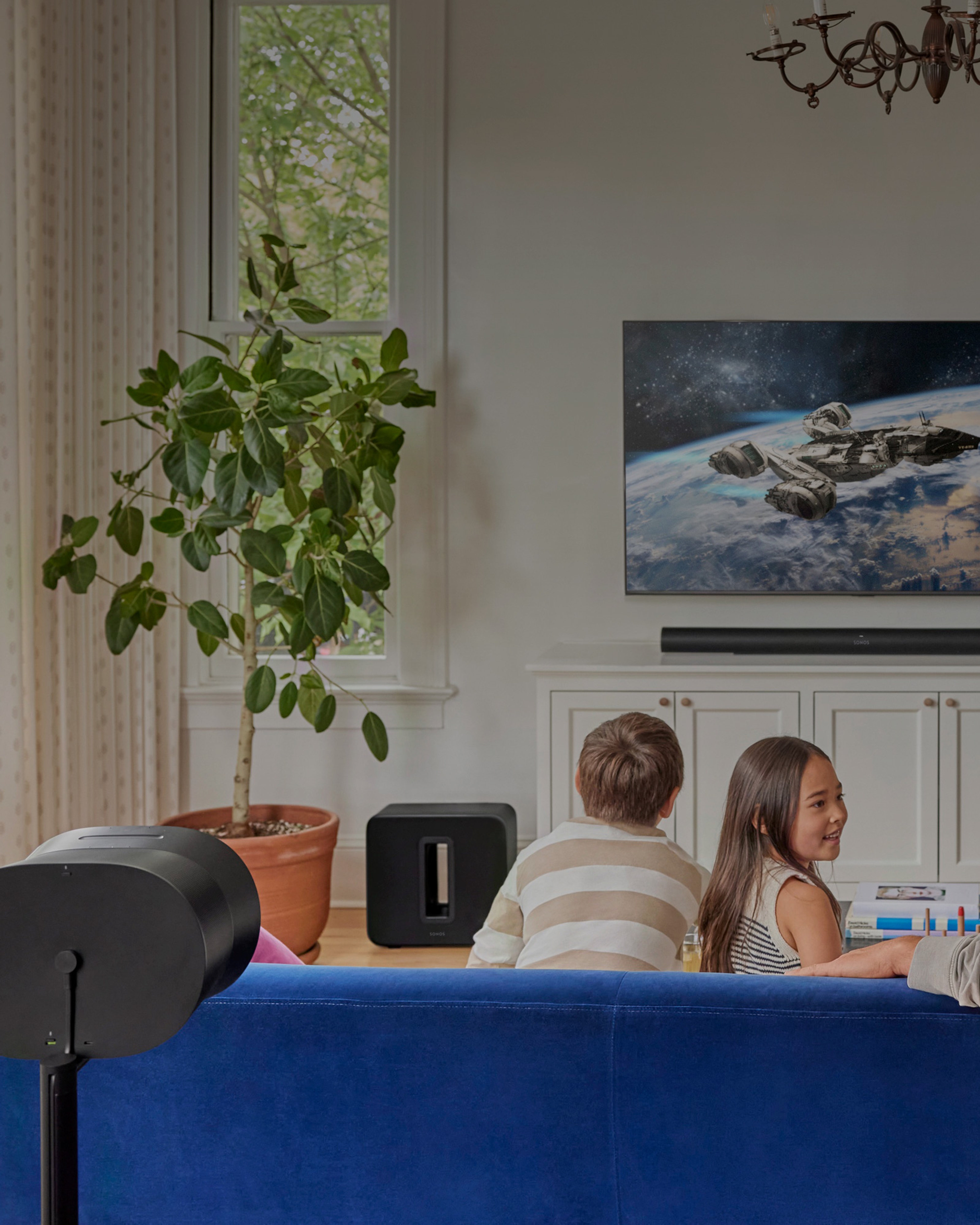 Family in the living room watching TV with Sonos Arc Ultra, Sub 4, Era 300 home theatre set
