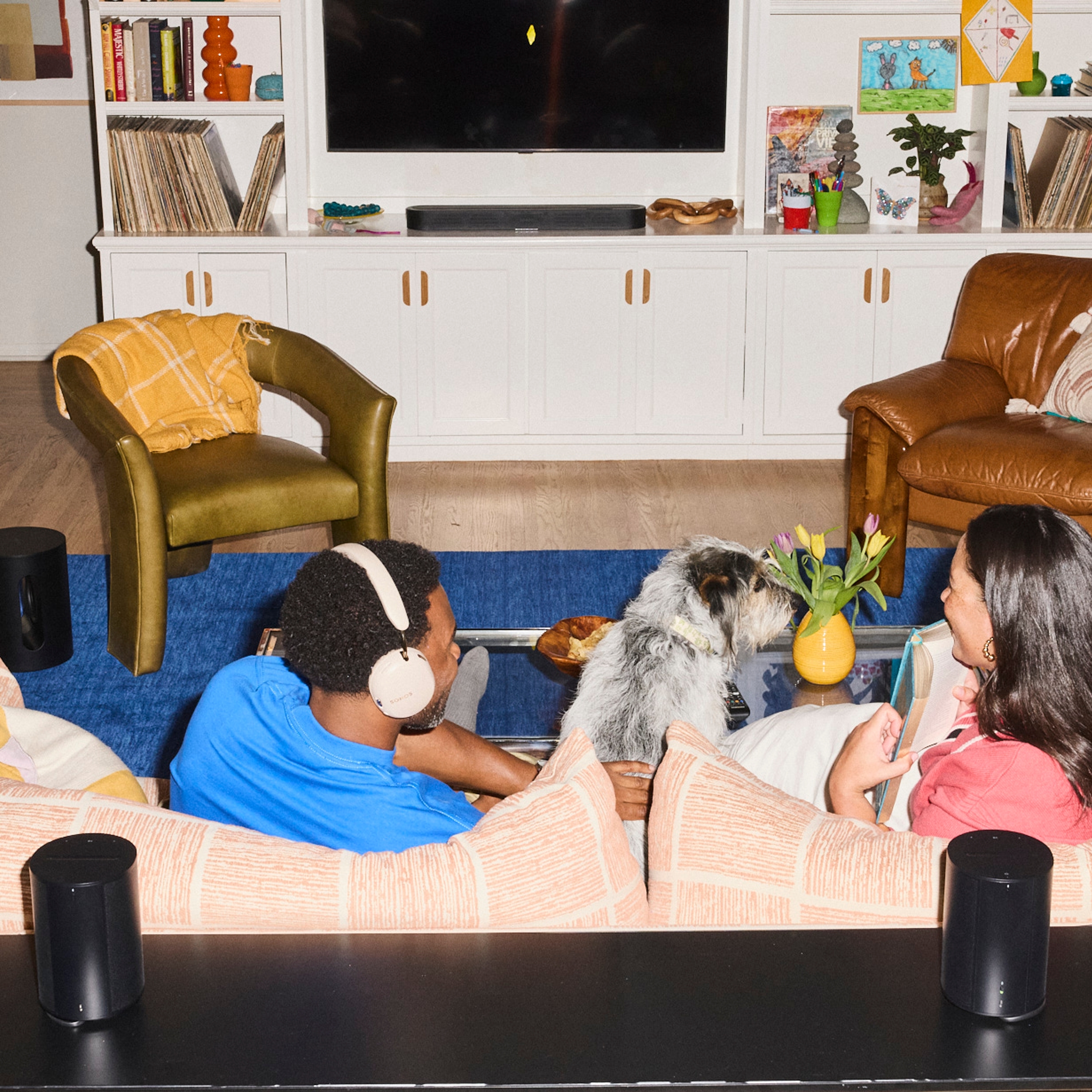 Two people sitting on a couch with a dog and a black Beam Ultra soundbar in a modern living room
