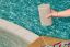 Main tenant un Sonos Play couleur Sand au-dessus de la piscine