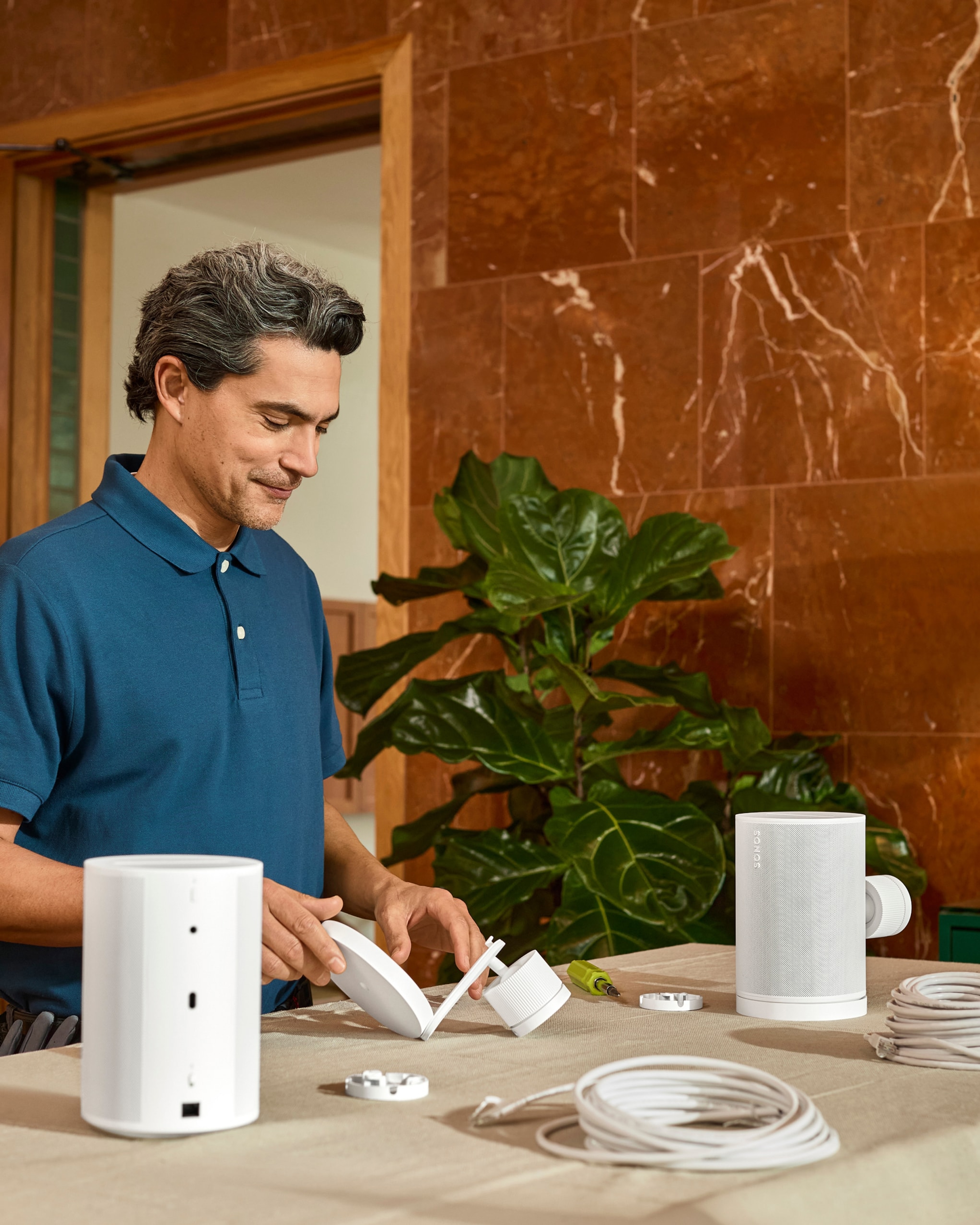 A certified installer assembling wall-mounts for a pair of white Era 100 Pro speakers