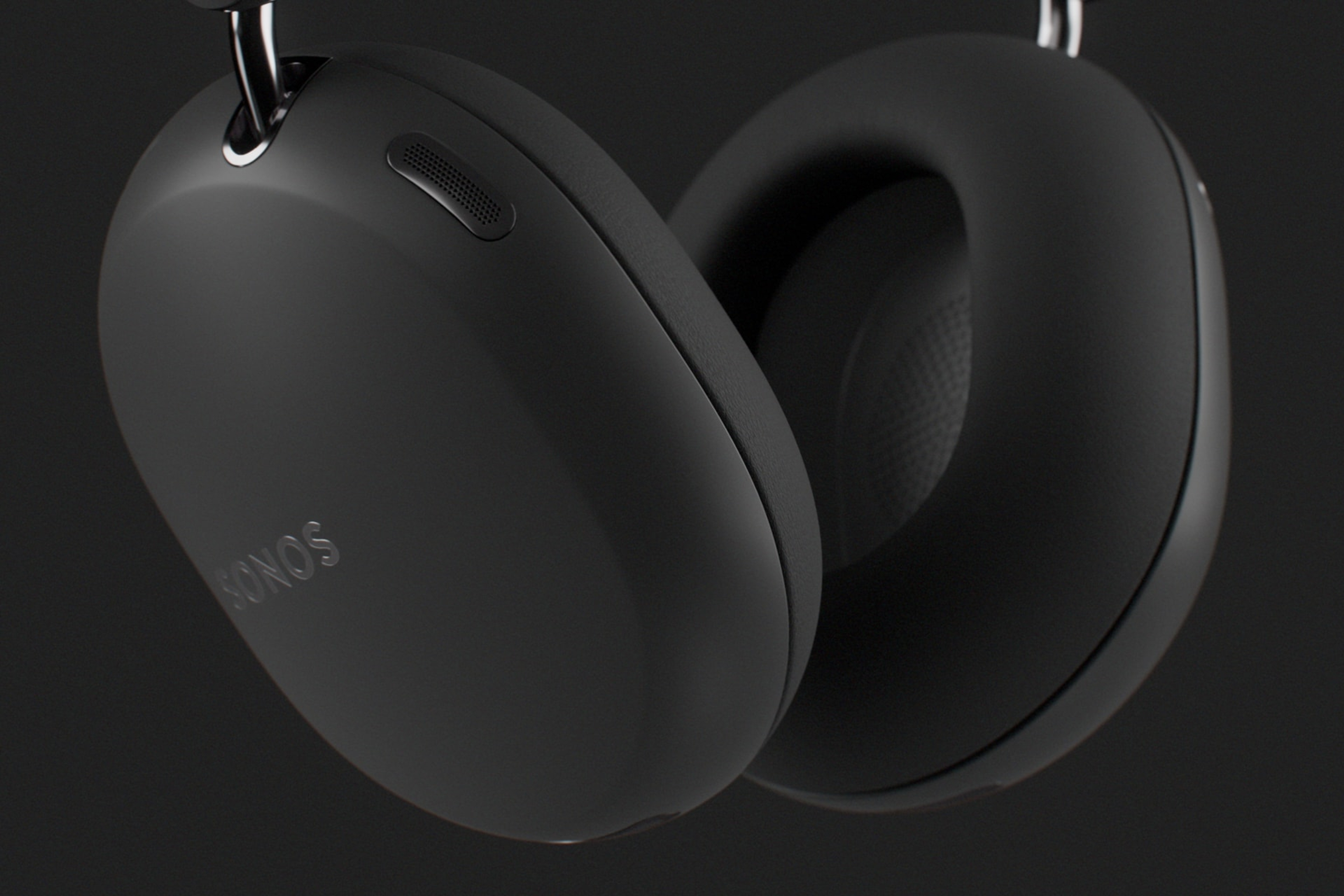 Closeup of the ear cups on a pair of black Sonos Ace Ultra headphones on a dark grey background