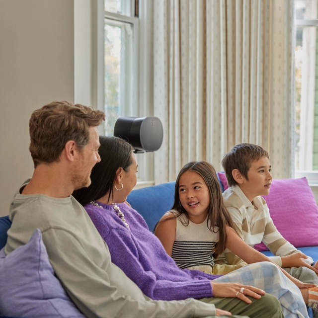 Family conversing on a couch in front of a black Era 300 on a stand