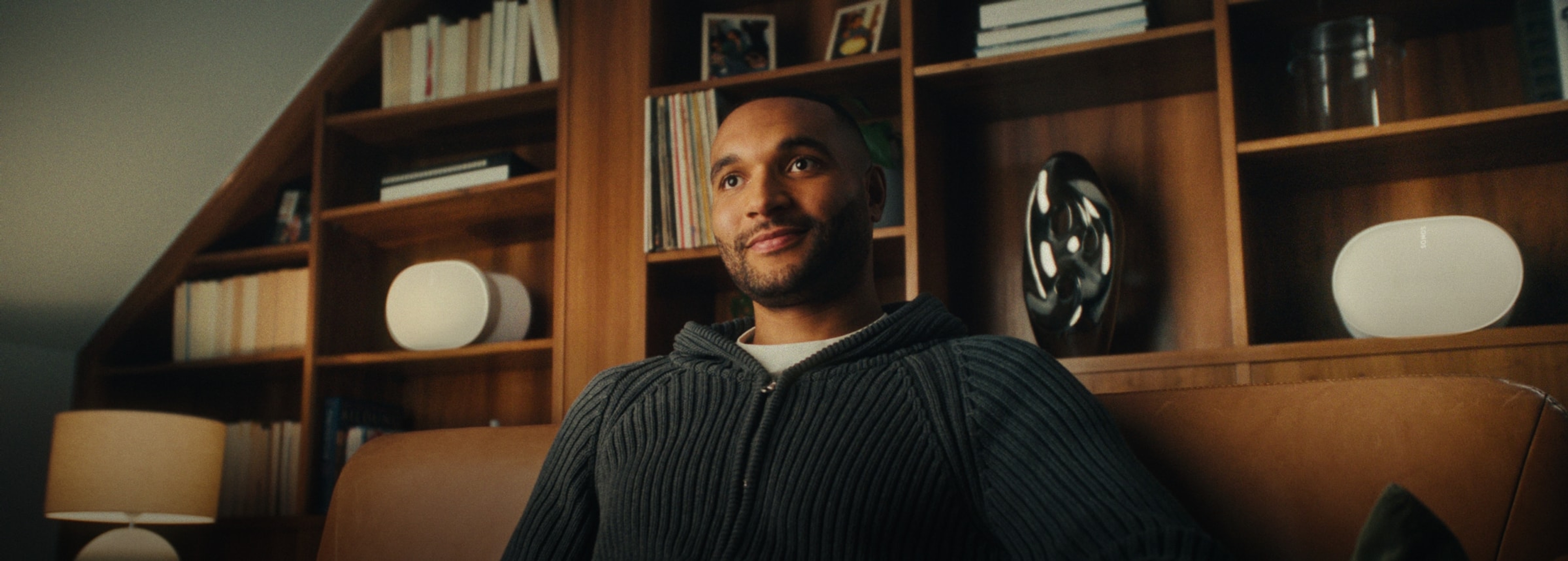 German footballer Jonathan Tah listening to a pair of white Sonos Era 300 speakers in his home