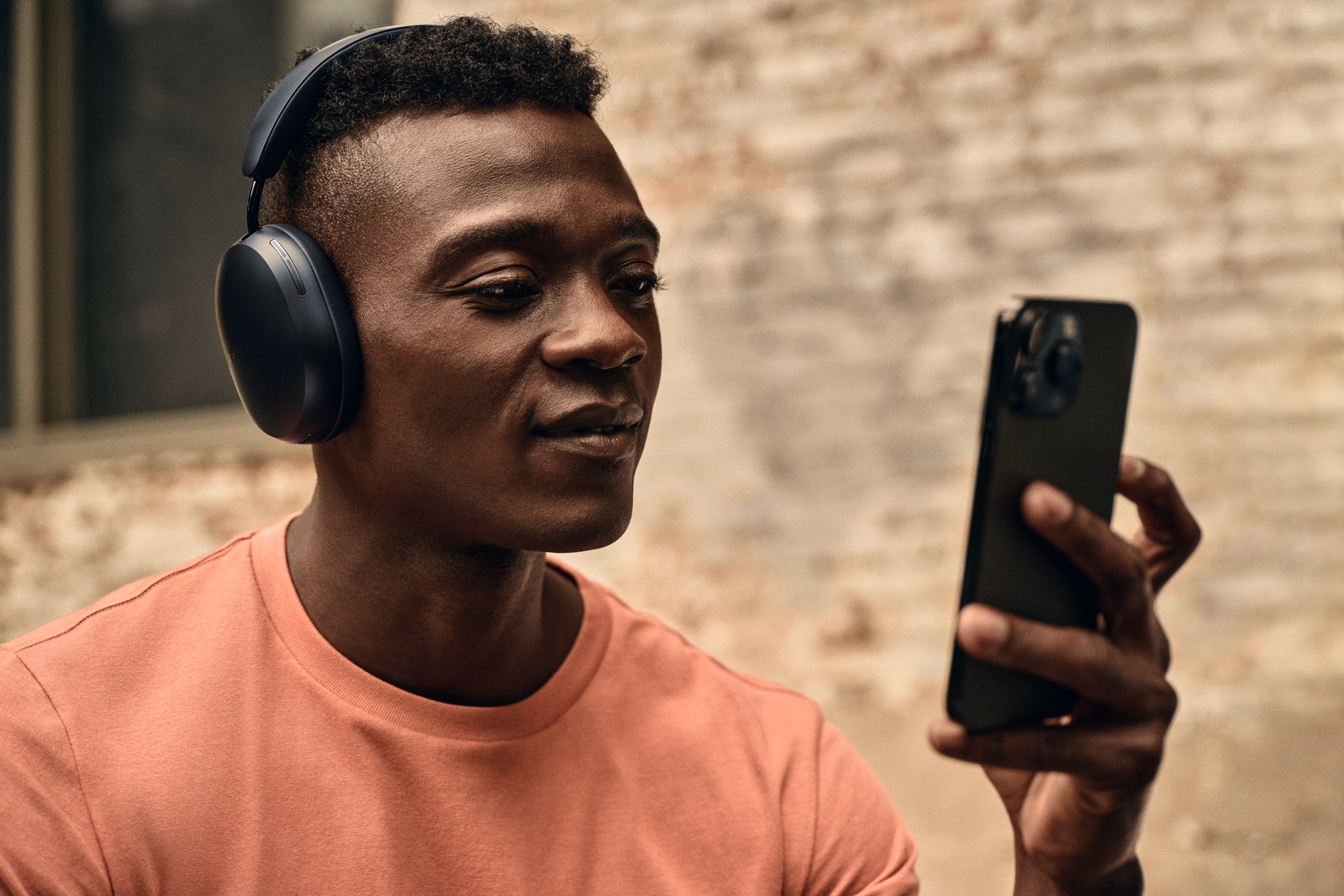 Man med telefon som lyssnar på svarta Sonos Ace-hörlurar